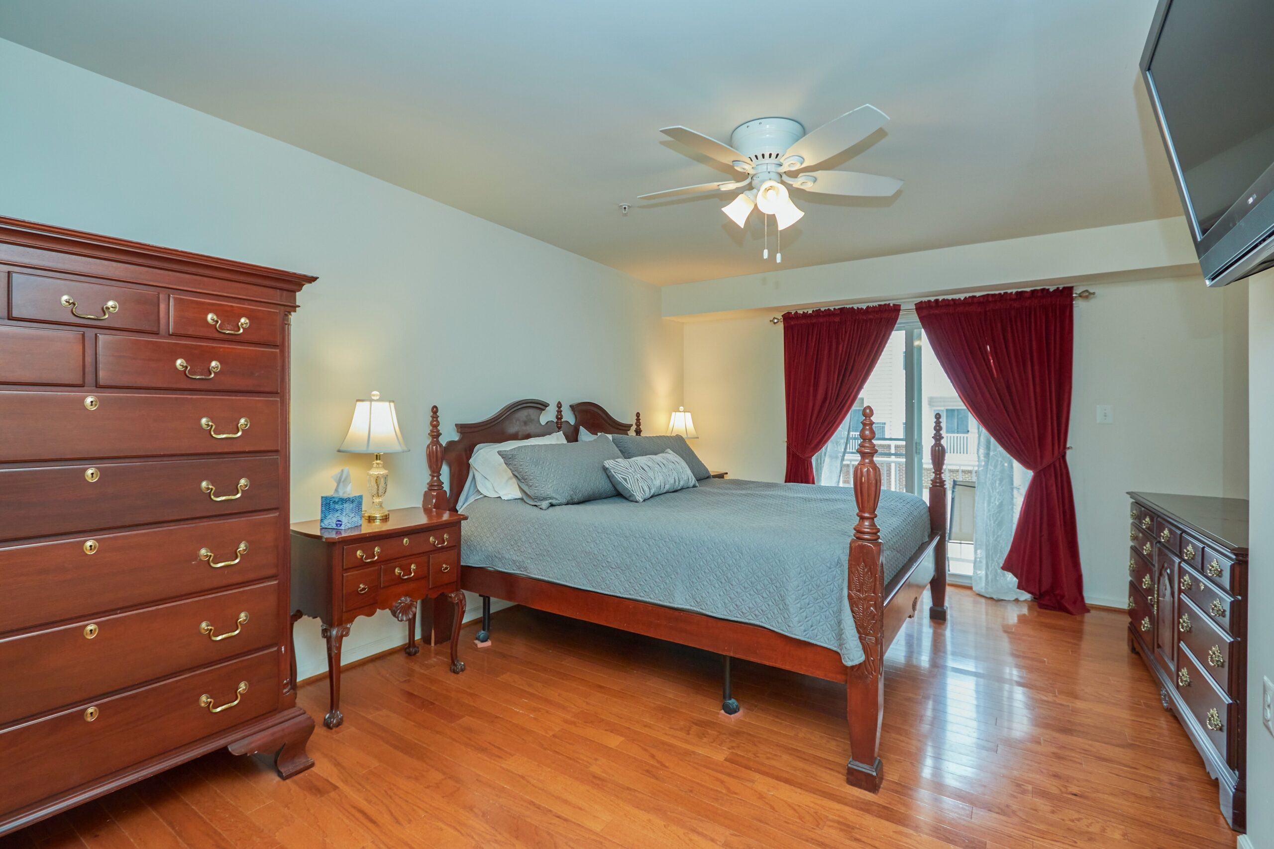 Professional interior photo of 6058 Aster Haven Circle - showing the primary bedroom with hardwood floors, ceiling fan, mounted tv