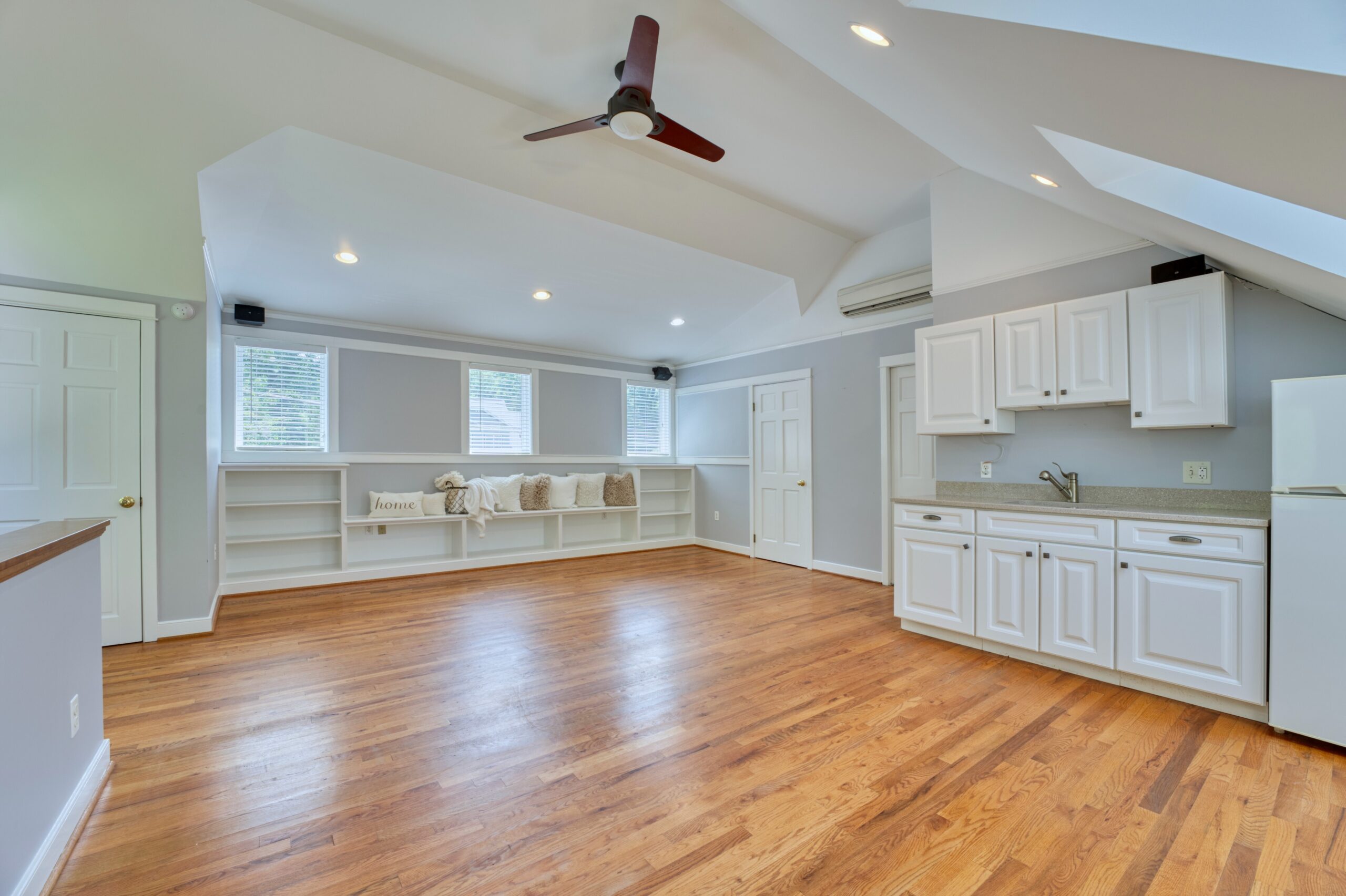 professional interior photo of 3132 Sleepy Hollow Road - showing the upper bonus room with built-in wet bar, shelves, and vaulted ceiling with ceiling fan and skylights over bamboo floors.