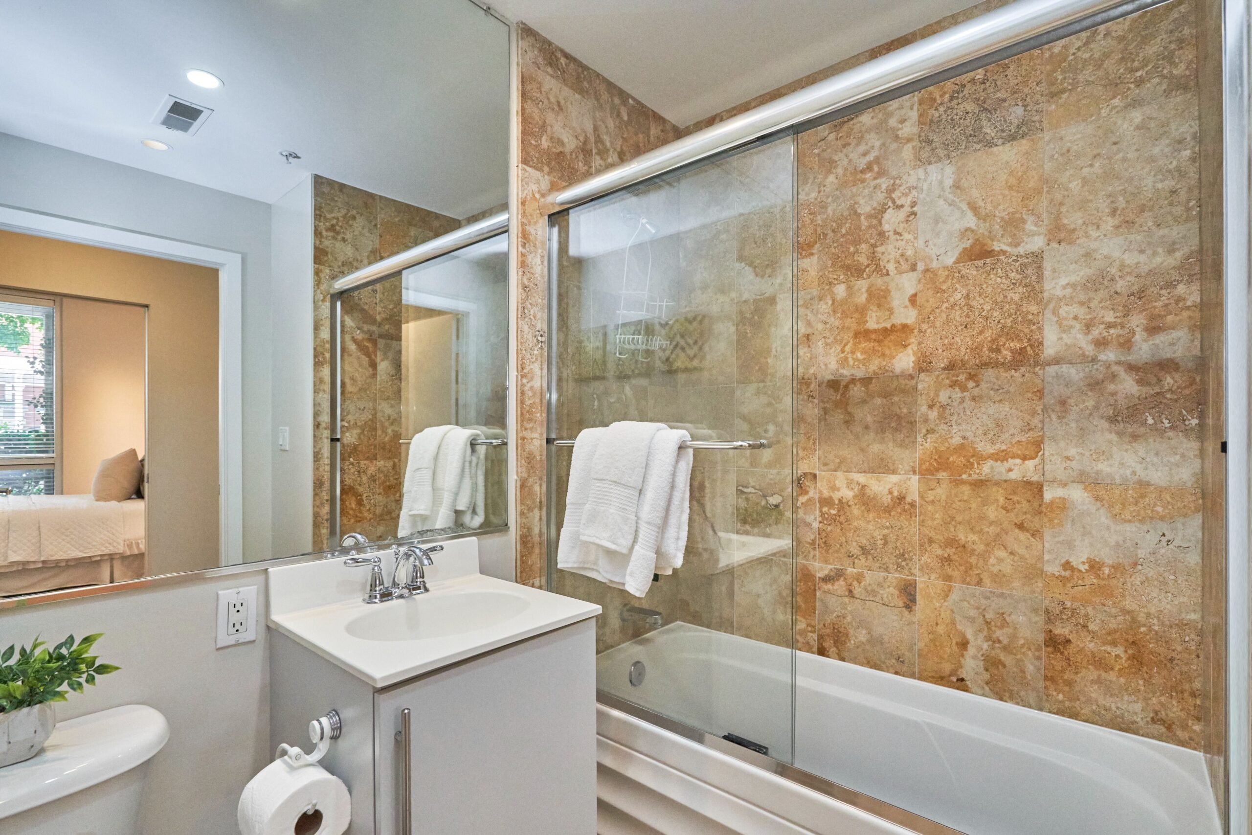 Professional interior photo of 1300 13th St NW #102, Washington DC - showing the primary bathroom with ceramic tiled walls over glass-enclosed bathtub