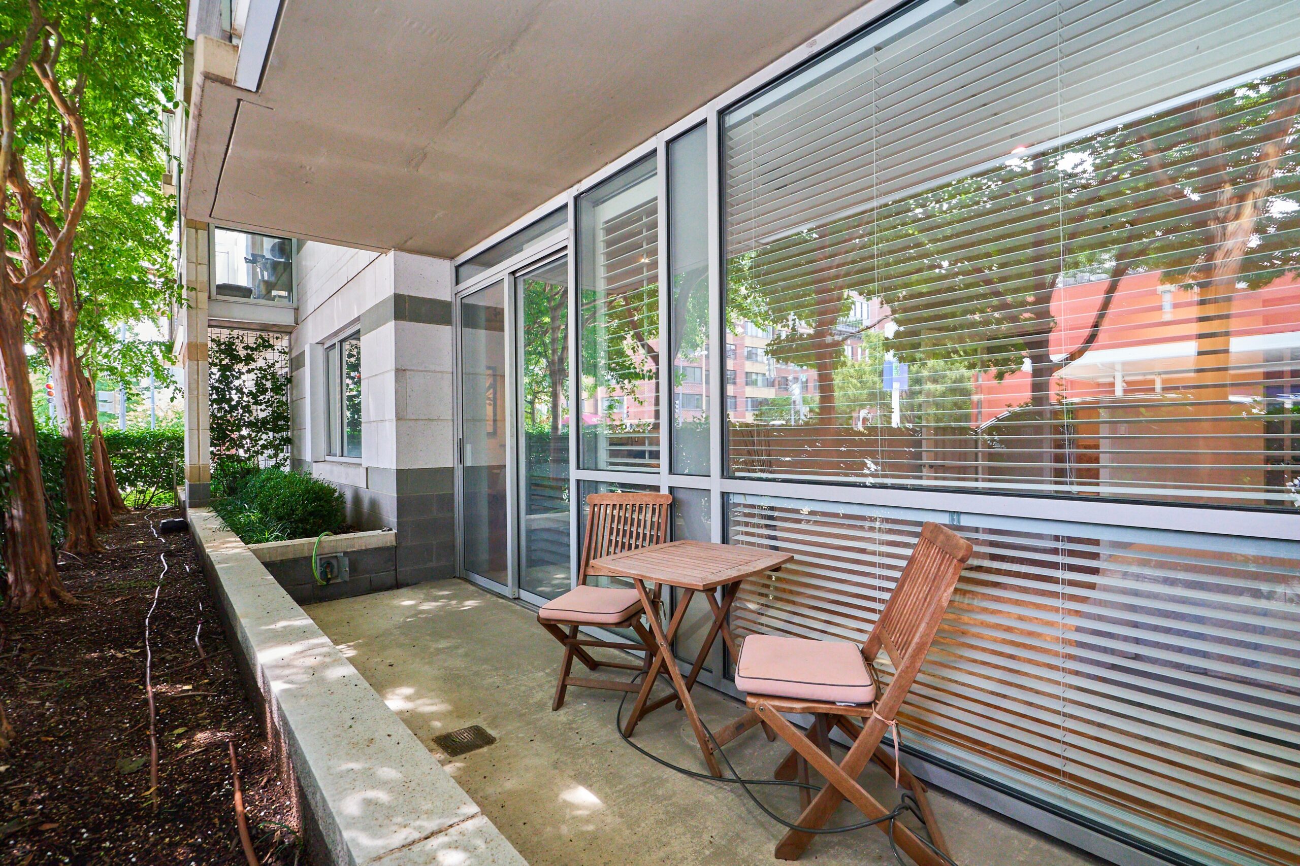 Professional exterior photo of 1300 13th St NW #102, Washington DC - showing the private patio with privacy shrubs