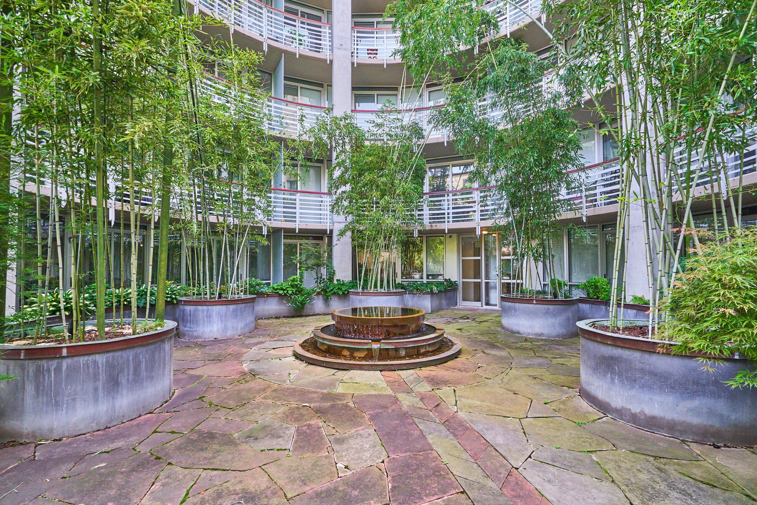 Professional exterior photo of 1300 13th St NW #102, Washington DC - showing the building's private courtyard and fountain