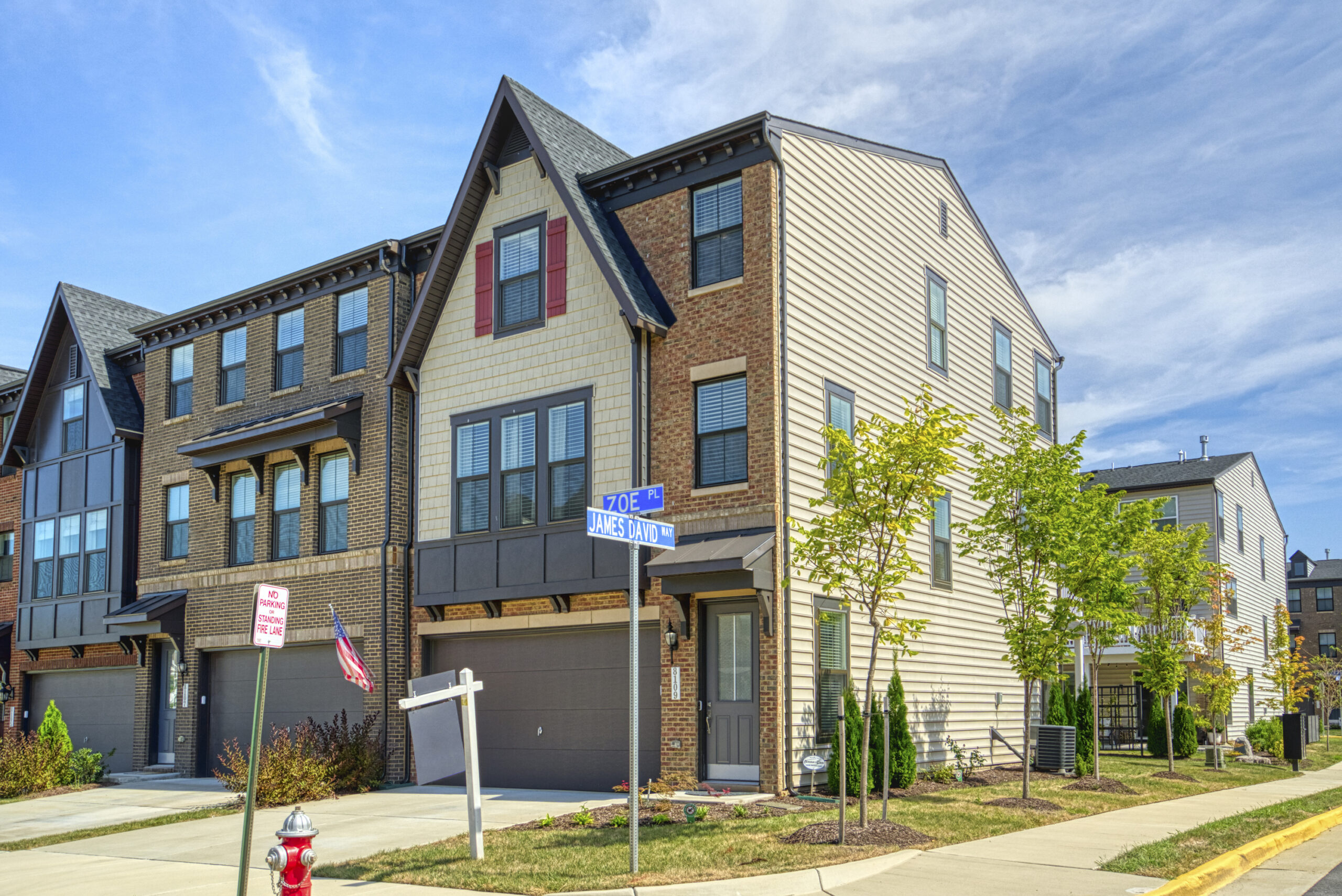 Professional exterior photo of 8109 Zoe Place, Alexandria, VA - Showing the front of the end-unit townhome with 2 car garage, brick and cream vinyl siding