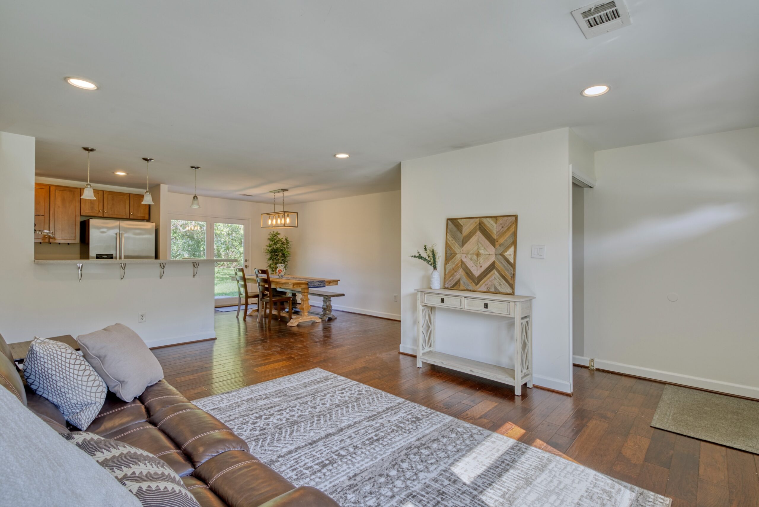 Professional interior photo of 1103 S Greenthorn Ave in Sterling, VA - showing the family room with hardwood floors, dining/kitchen in the background