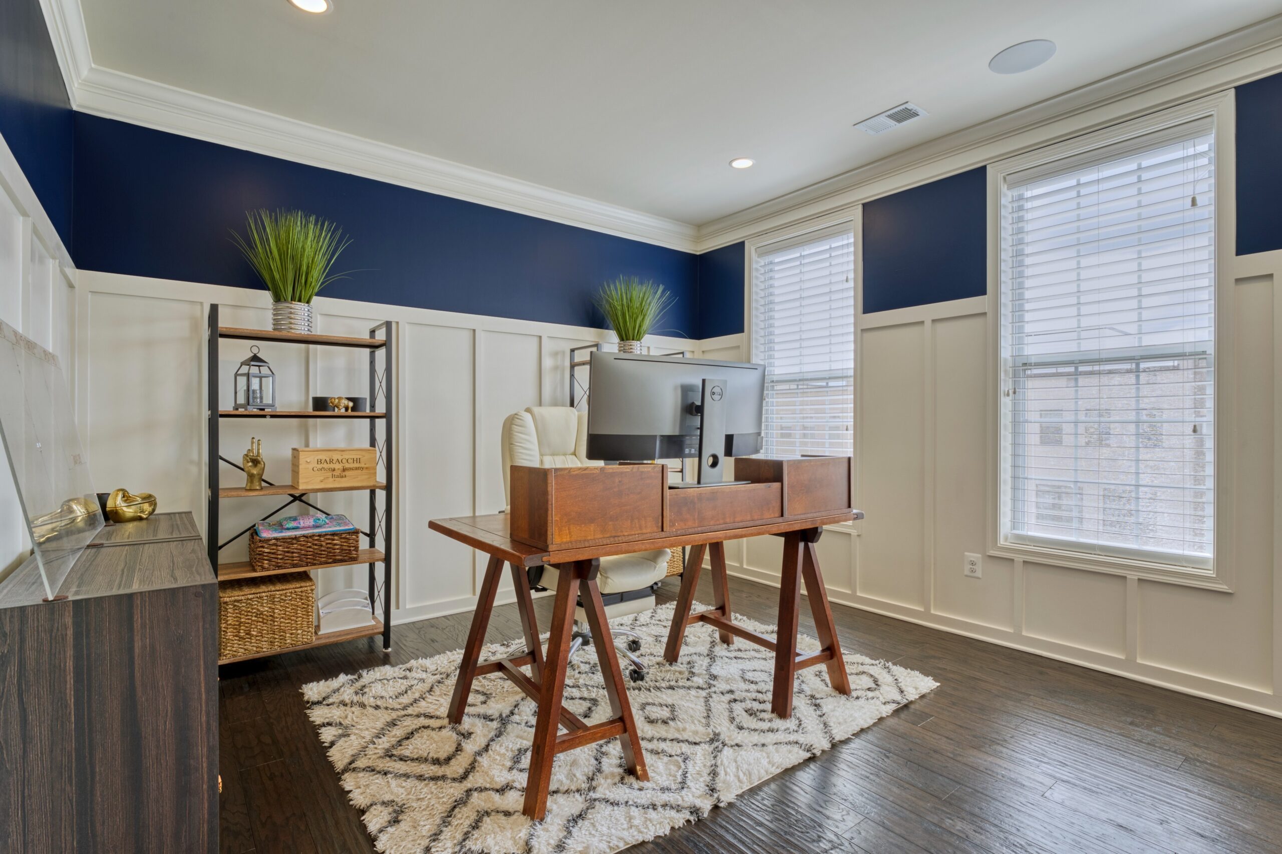 Professional interior photo of 23560 Buckland Farm Ter, Ashburn, VA - Showing the open office room with white wainscoting against white walls bordered by deep blue around the top third of the wall over the wainscoting