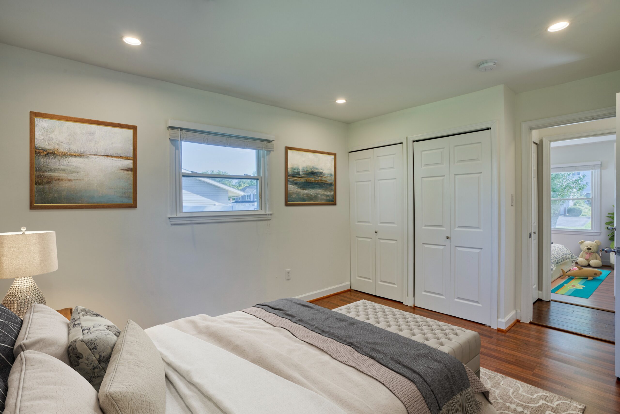 Professional interior photo of 1103 S Greenthorn Ave in Sterling, VA - showing a bedroom with hardwood floors and double door closet which has been virtually staged as a bedroom and second bedroom visible through the hallway has been virtually staged with kids items as well