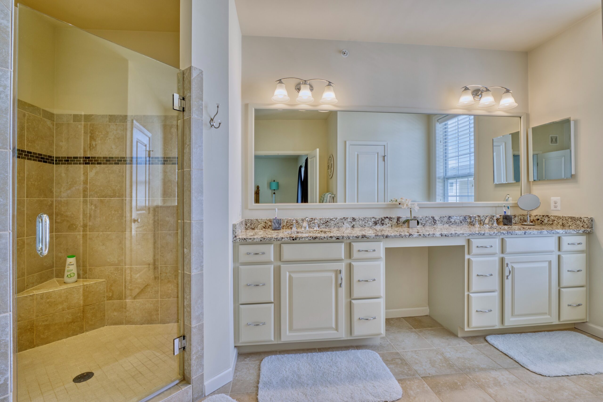 Professional interior photo of 23560 Buckland Farm Ter, Ashburn, VA - Showing the primary bathroom with large tiled shower with bench and dual-vanity with granite counters