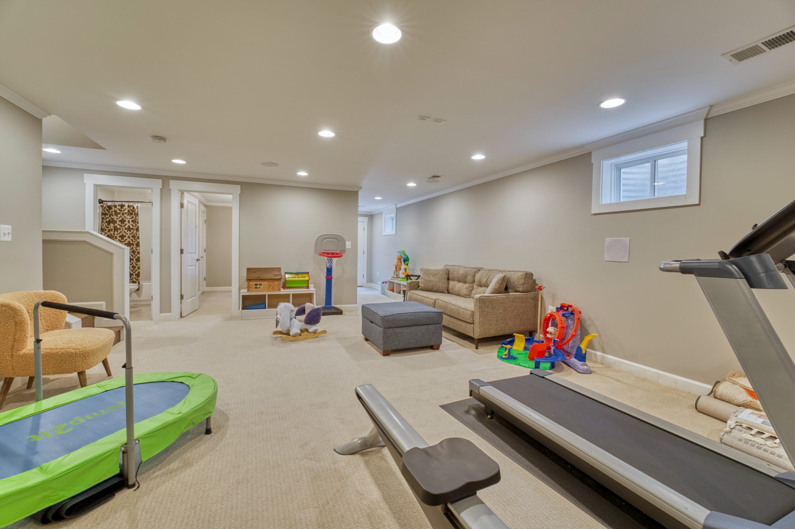 Professional interior photo of 505 N West St - showing the basement with neutral walls and carpeting, high window, and doors to office and full bathroom
