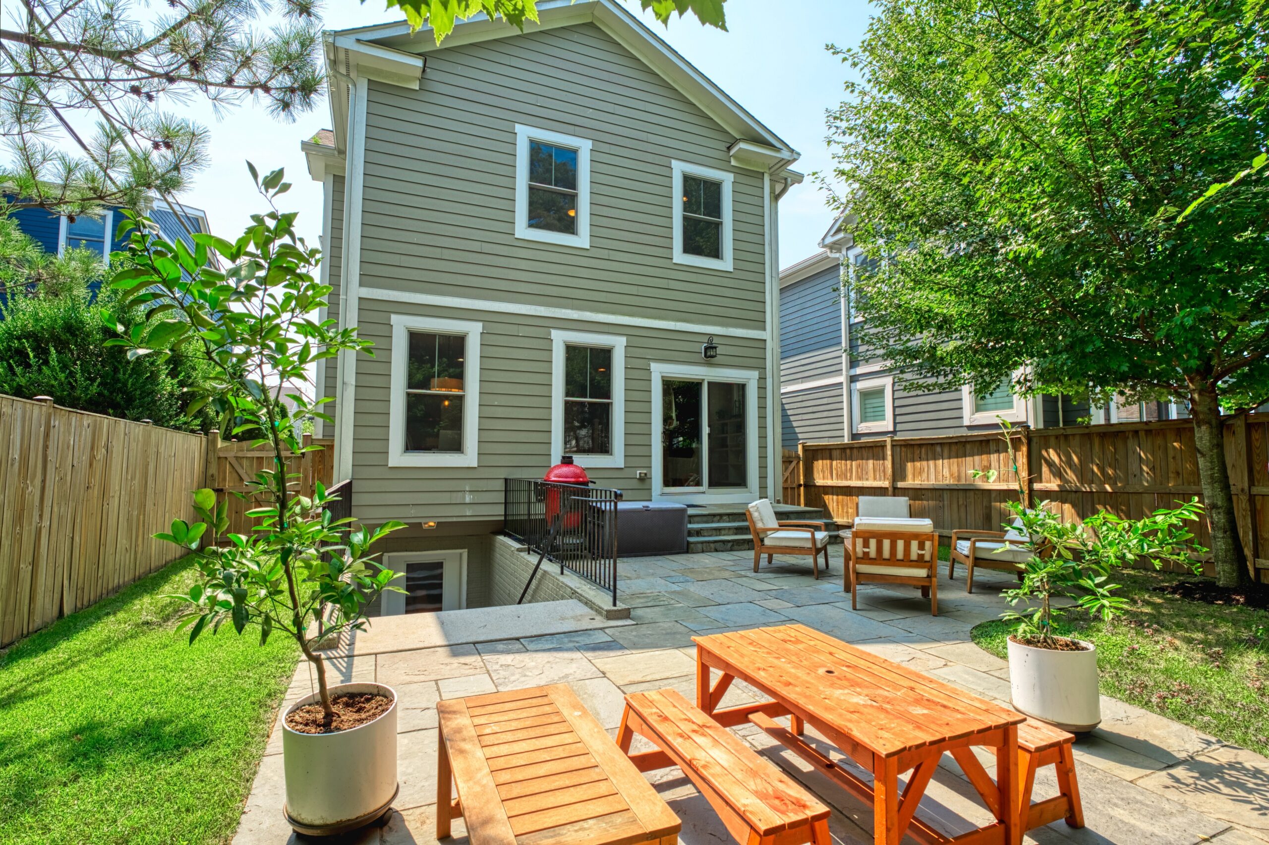 Professional exterior photo of 505 N West St - showing the rear view from the backyard just off the patio, with child size picnic table and benches, stairs down to the walkout basement and other patio furniture near main rear door