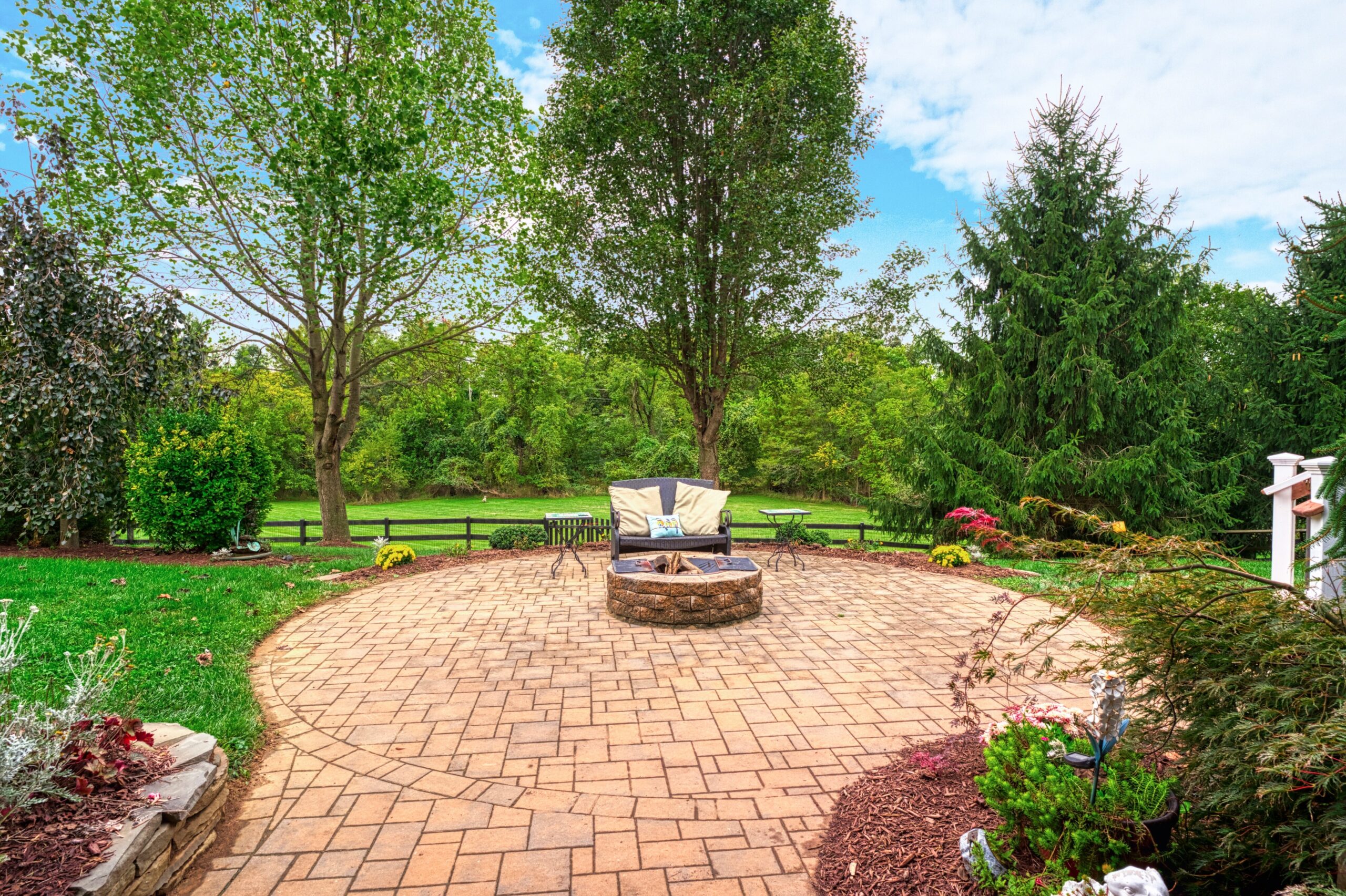 Professional exterior photo of 16961 Heather Knolls Pl - showing the circular stone patio with fire pit inside a fenced backyard