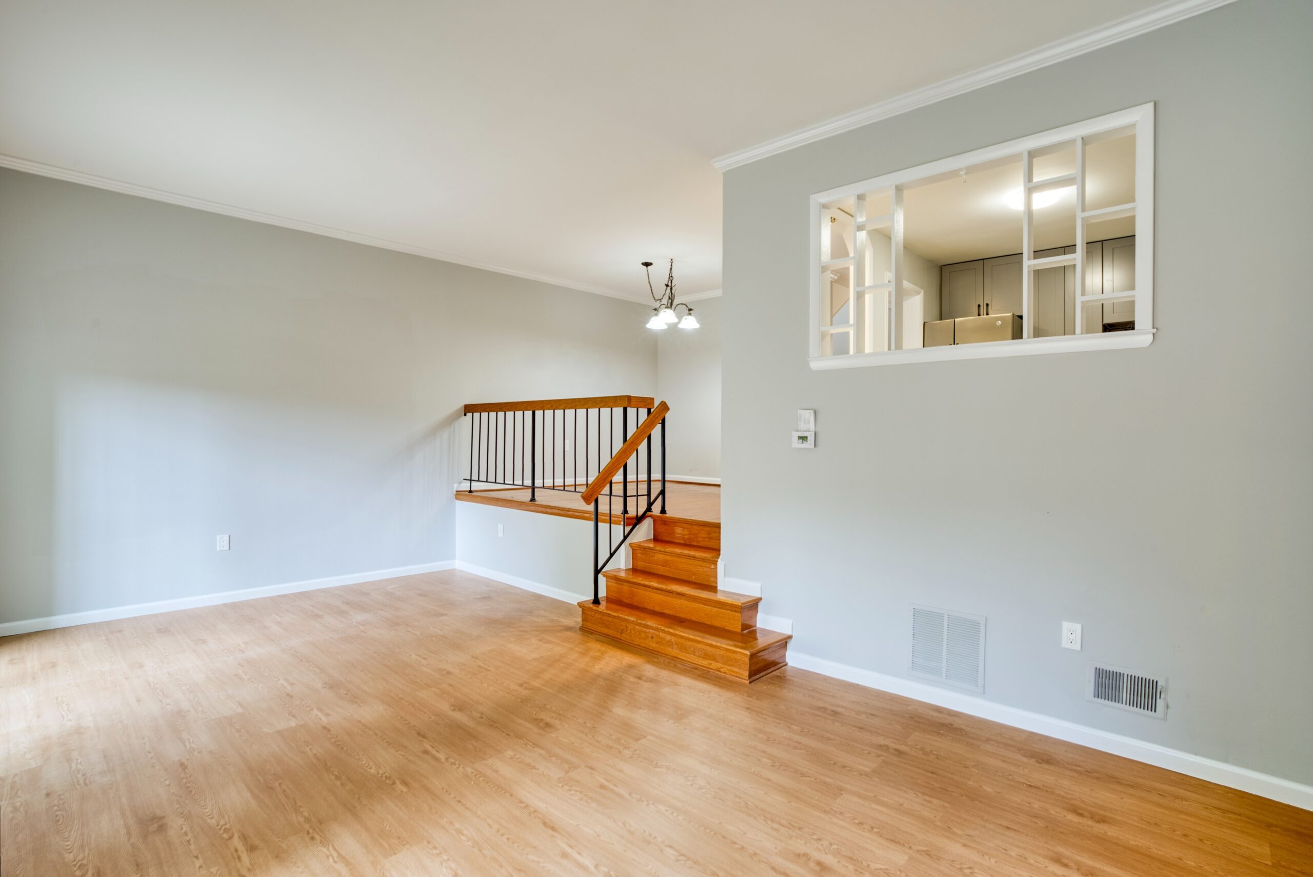 Professional interior photo of 6302 Arwen Court, Fort Washington, MD - showing the living room with 4 stairs up to the dining room and window of the kitchen overlooking the living room