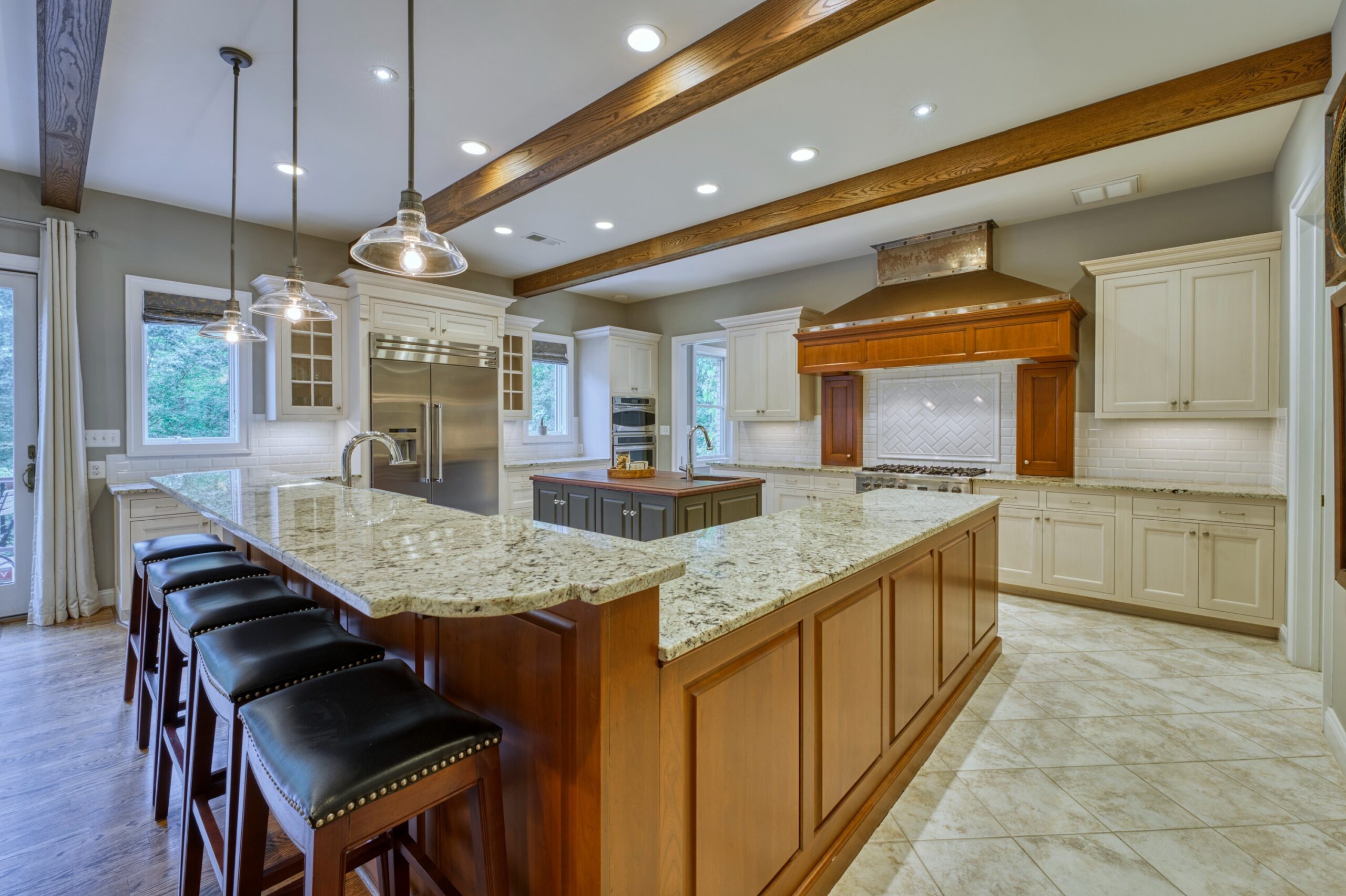 Professional interior photo of 40046 Mount Gilead Rd in Leesburg, Virginia - showing the kitchen with large gas stove and huge custom range hood and island with farm sink and butcher block counter. 
