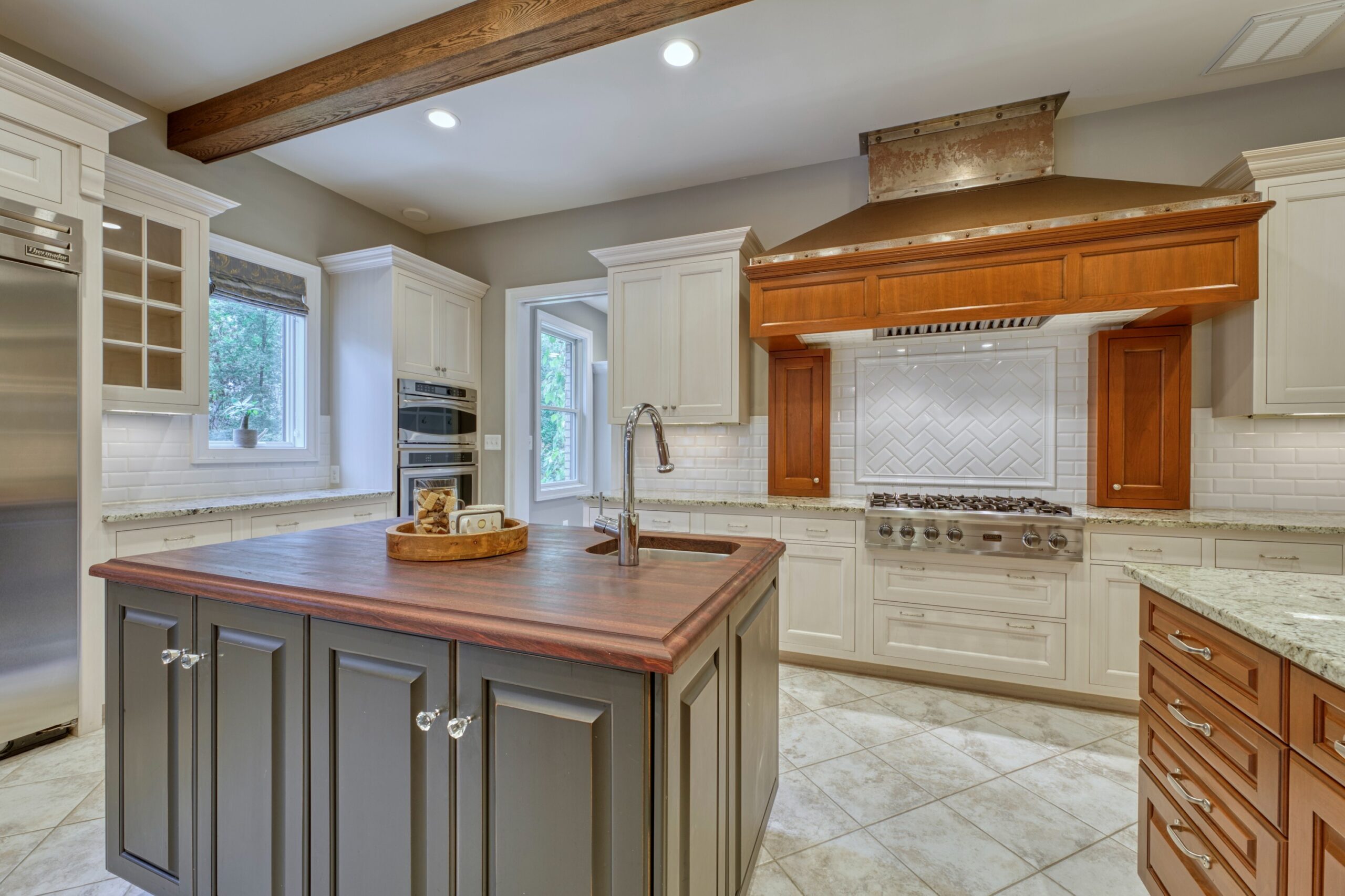 Professional interior photo of 40046 Mount Gilead Rd in Leesburg, Virginia - showing the kitchen with large gas stove and huge custom range hood and island with farm sink and butcher block counter. 