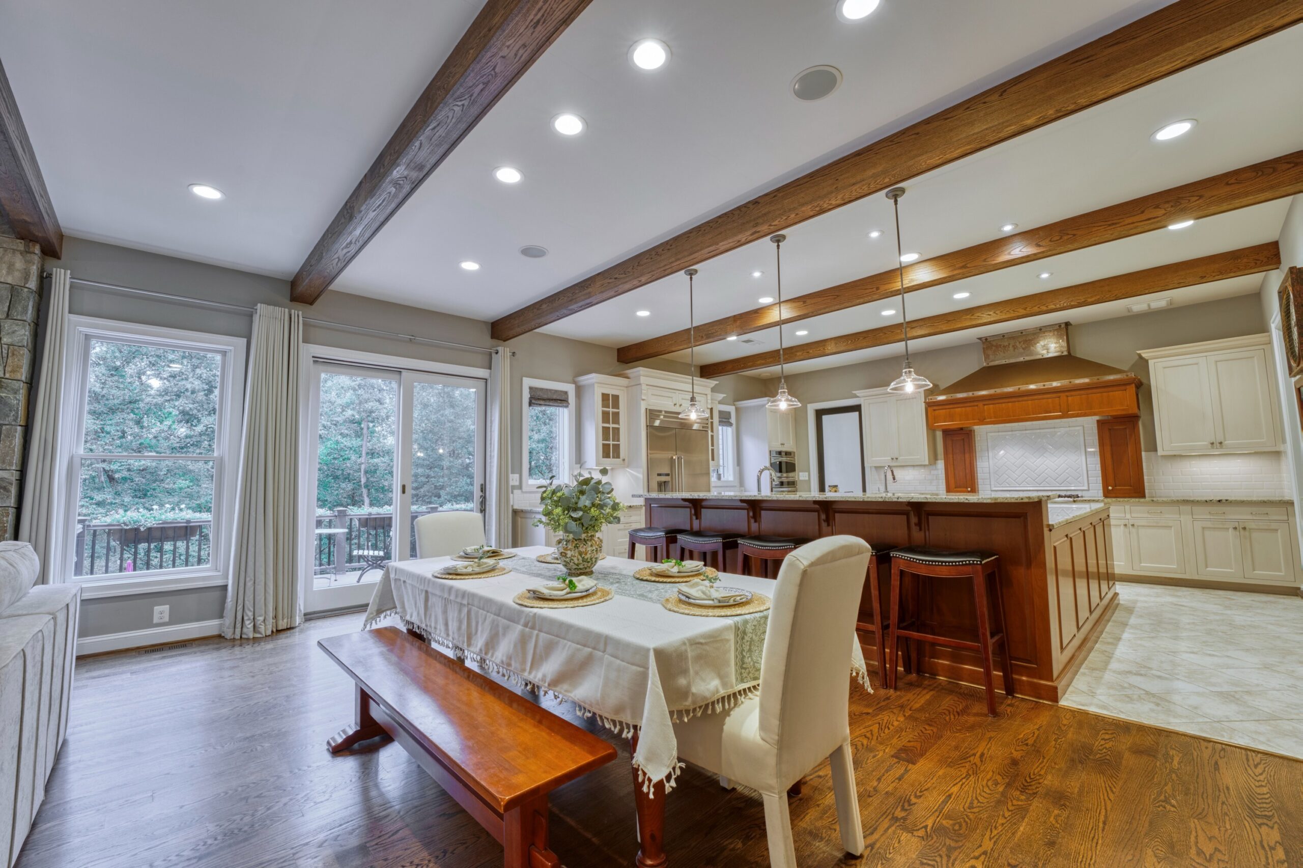 Professional interior photo of 40046 Mount Gilead Rd in Leesburg, Virginia - showing the kitchen table next to the large kitchen bar with 5 barstools and exposed beams in the otherwise white ceiling