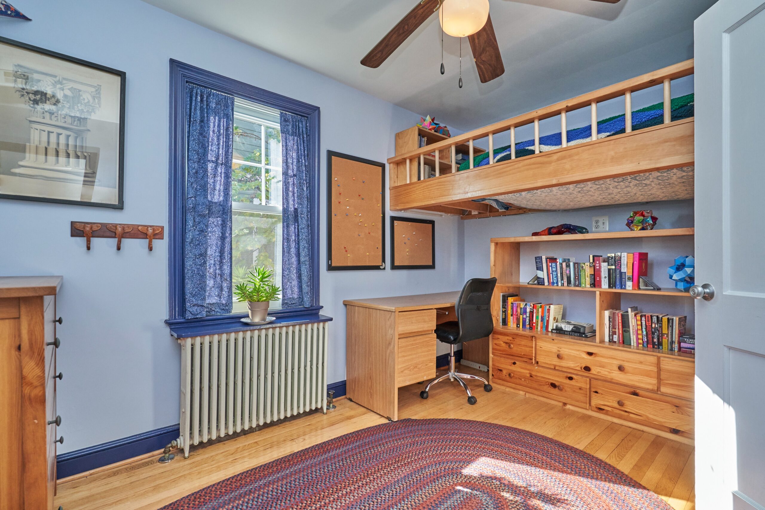 Professional interior photo of 15 N Fenwick Street - showing a bedroom with built in bookshelves and raised bed built in just below the ceiling over the desk and shelves