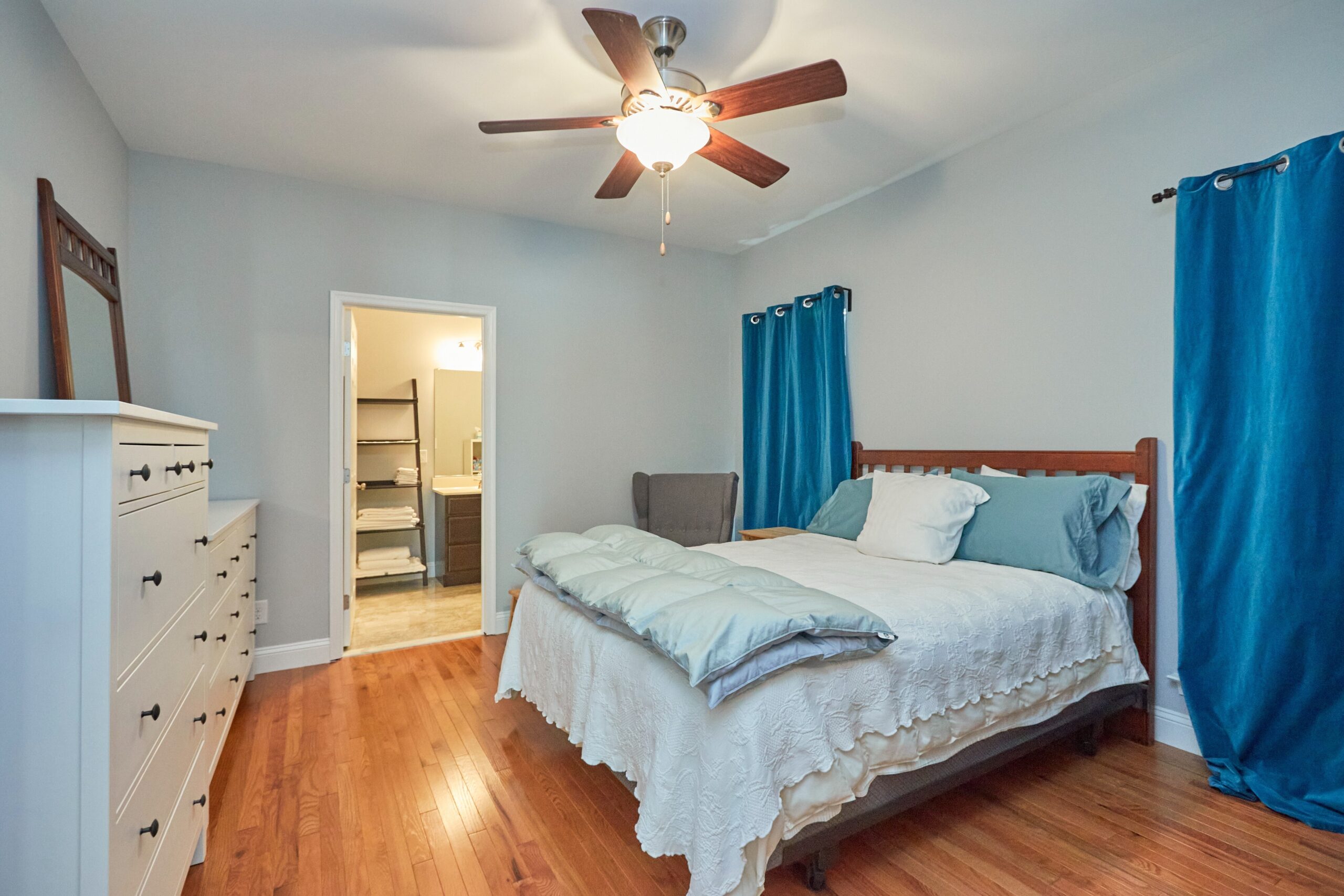 Professional interior photograph of 384 C Street - showing the primary bedroom with hardwood floors, ceiling fan, and door to ensuite bathroom