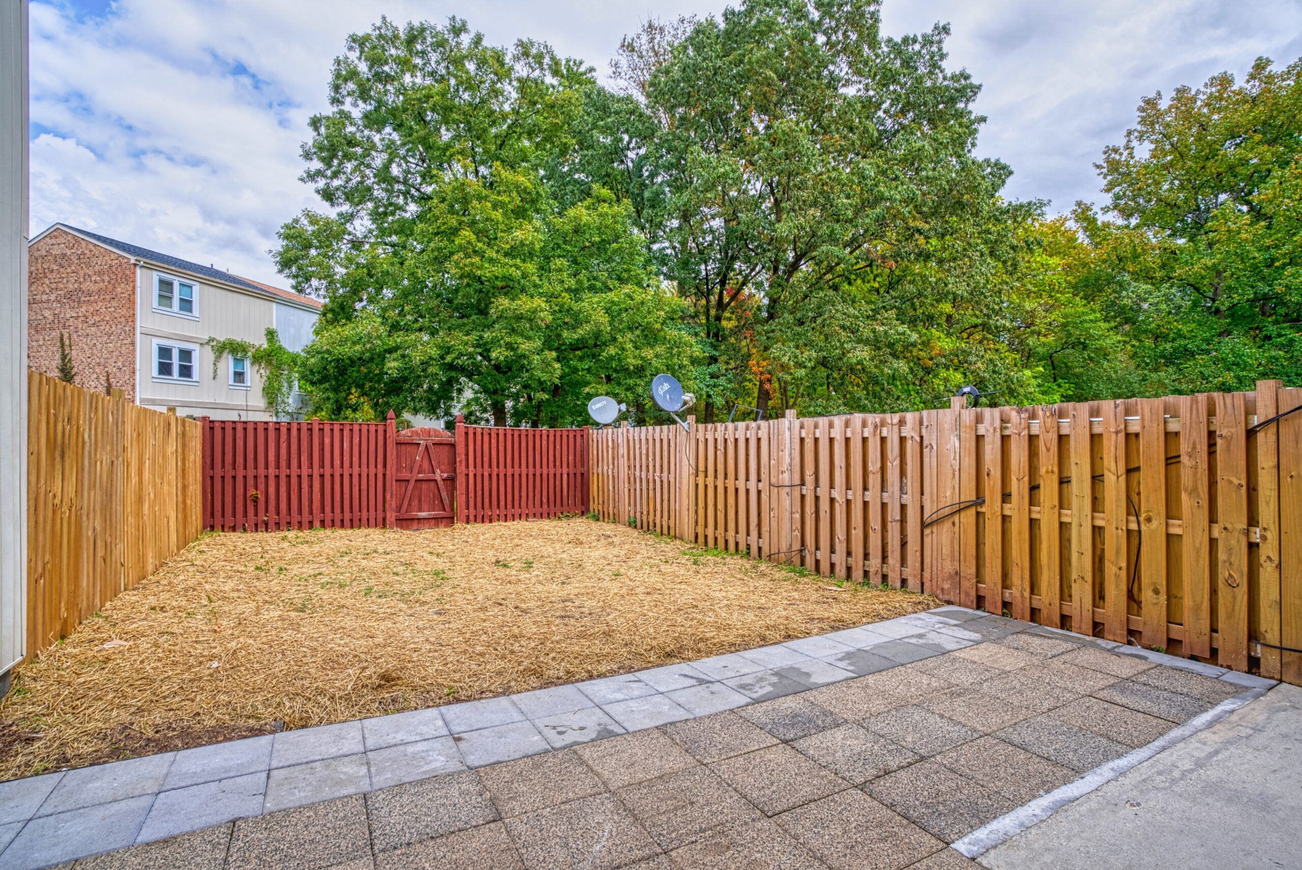 Professional exterior photo of 6302 Arwen Court, Fort Washington, MD - showing the view from the rear door across the patio to the grassy area and rear red fence