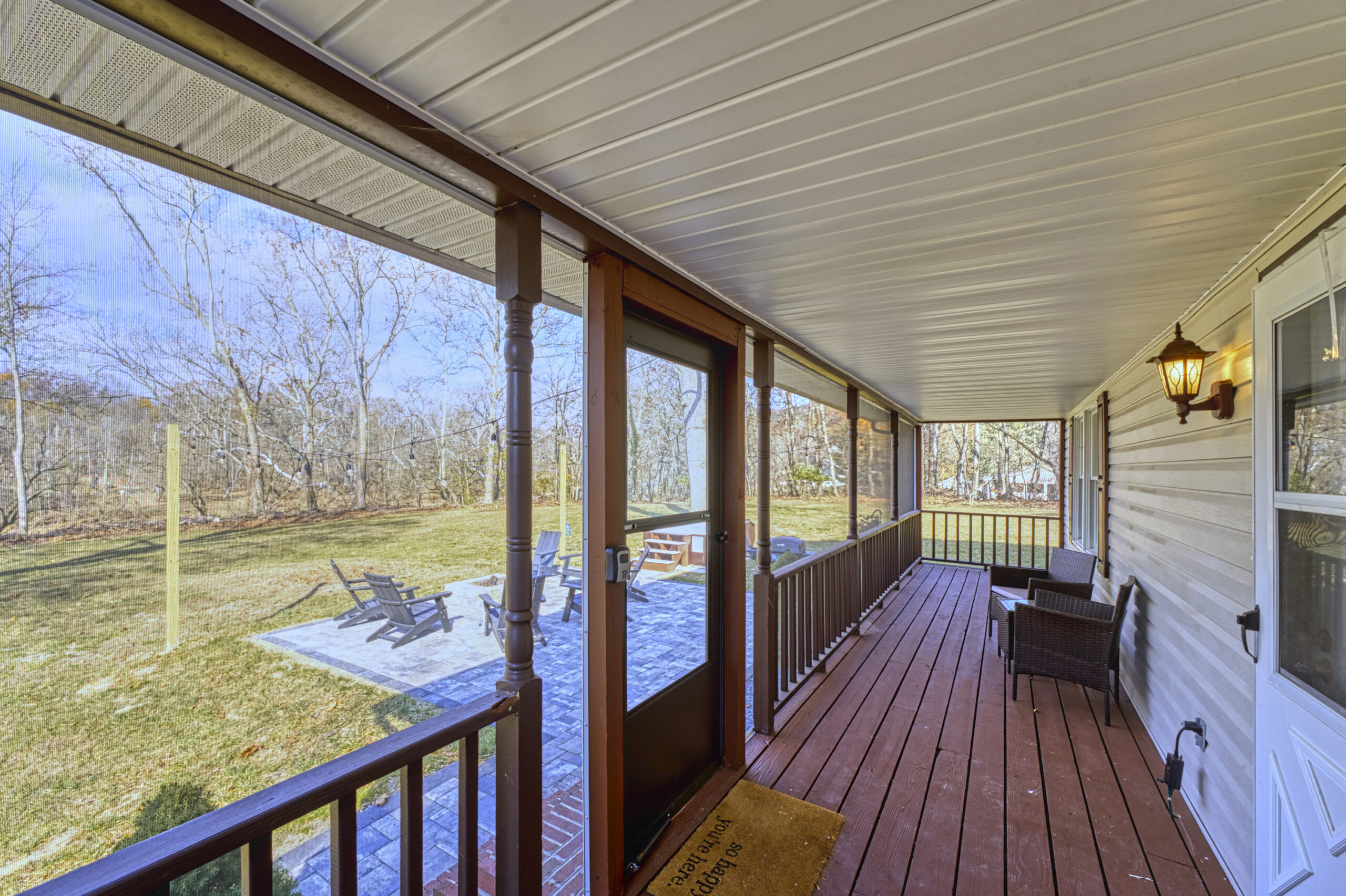 Professional exterior photo of 4809 Grove Hill River Rd - showing the interior of the front screened porch looking over the flat front yard with stone patio
