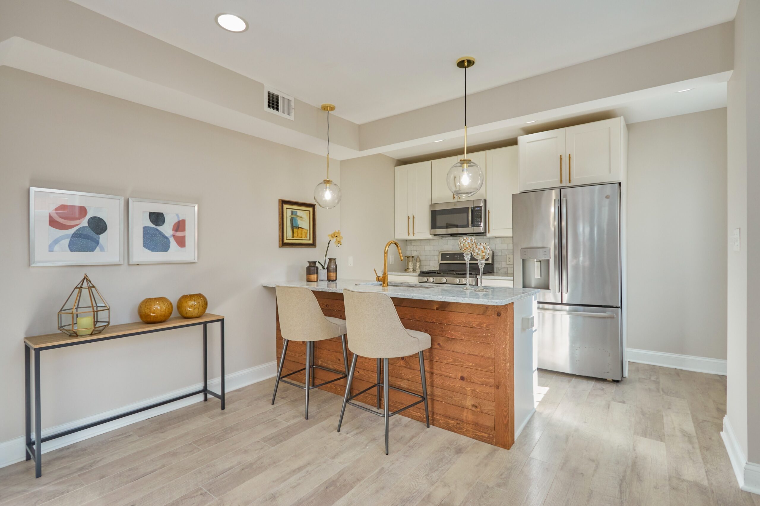 Professional interior photo of 1219 50th St NE in Washington, DC - showing the fully remodeled kitchen with quartz countertop island/peninsula and bar with white cabinets, stainless appliances and brushed cold hardware