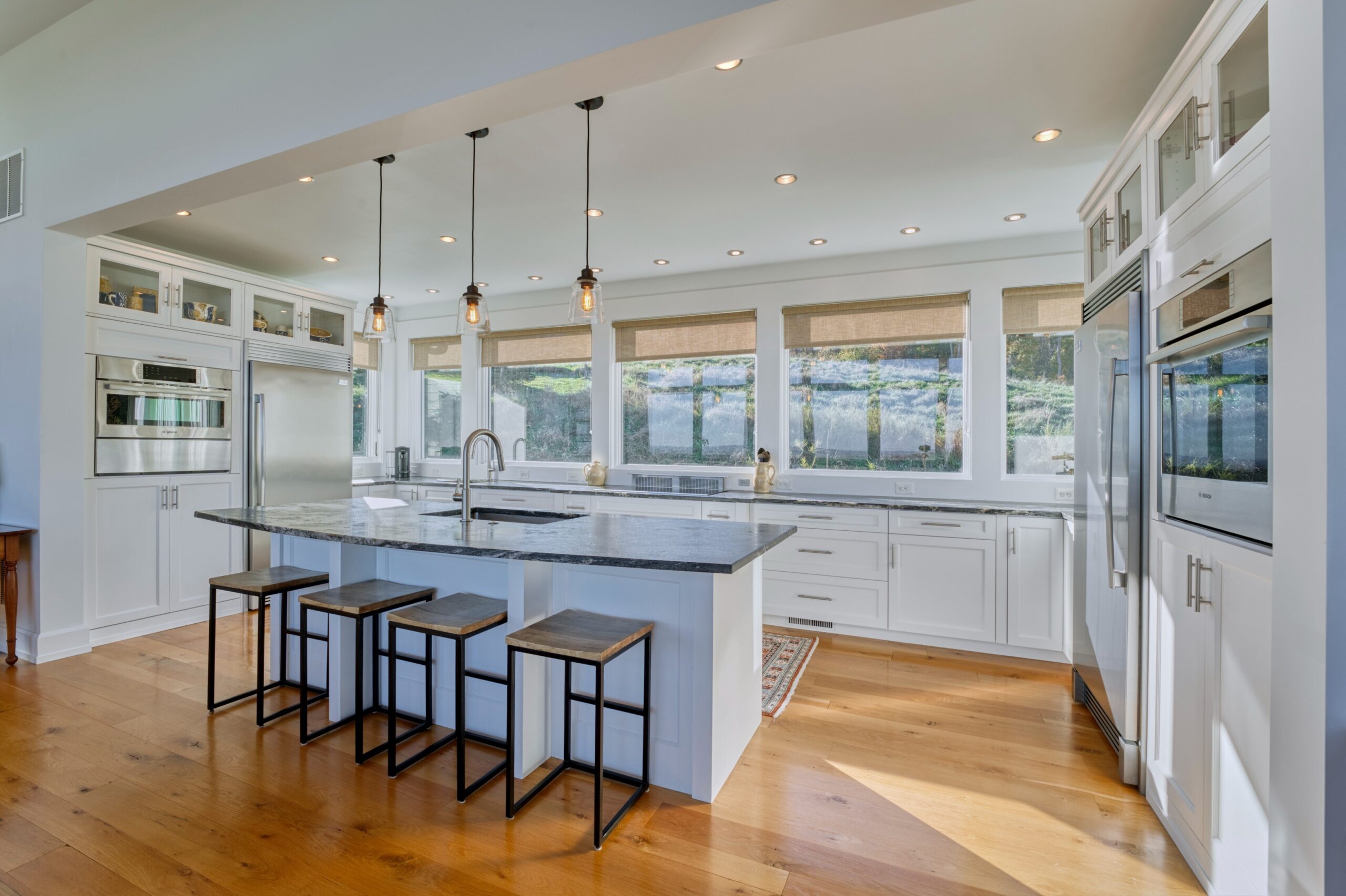 Professional interior photo of 17151 Brookdale Ln in Round Hill, VA - showing the kitchen with stone countertops, high-end stainless appliances, large island with bar and barstools and inset farmers sink