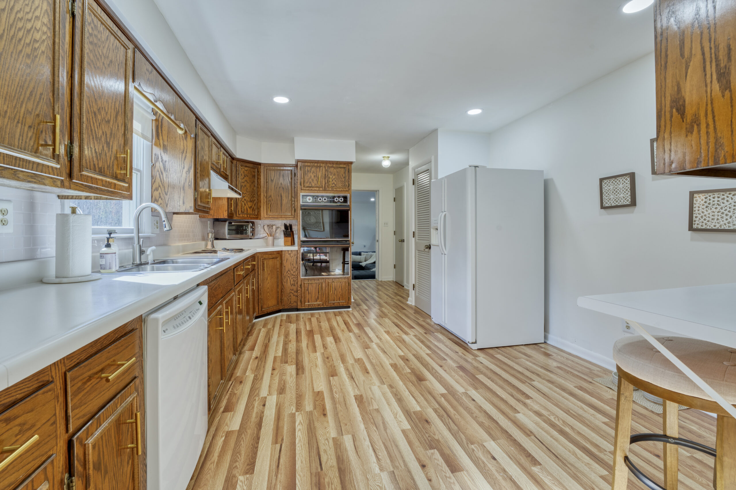 Professional interior photo of 4809 Grove Hill River Rd - showing the kitchen with LVP floors, oak cabinets, white appliances and a breakfast bar