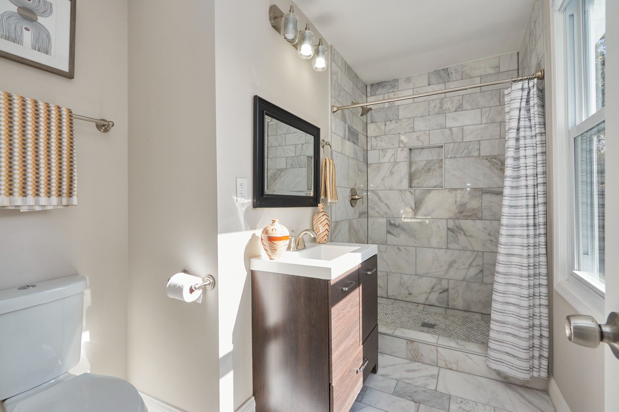 Professional interior photo of 1219 50th St NE in Washington, DC - showing one of the 2 full bathrooms with an updated tiled shower with recessed soap holder