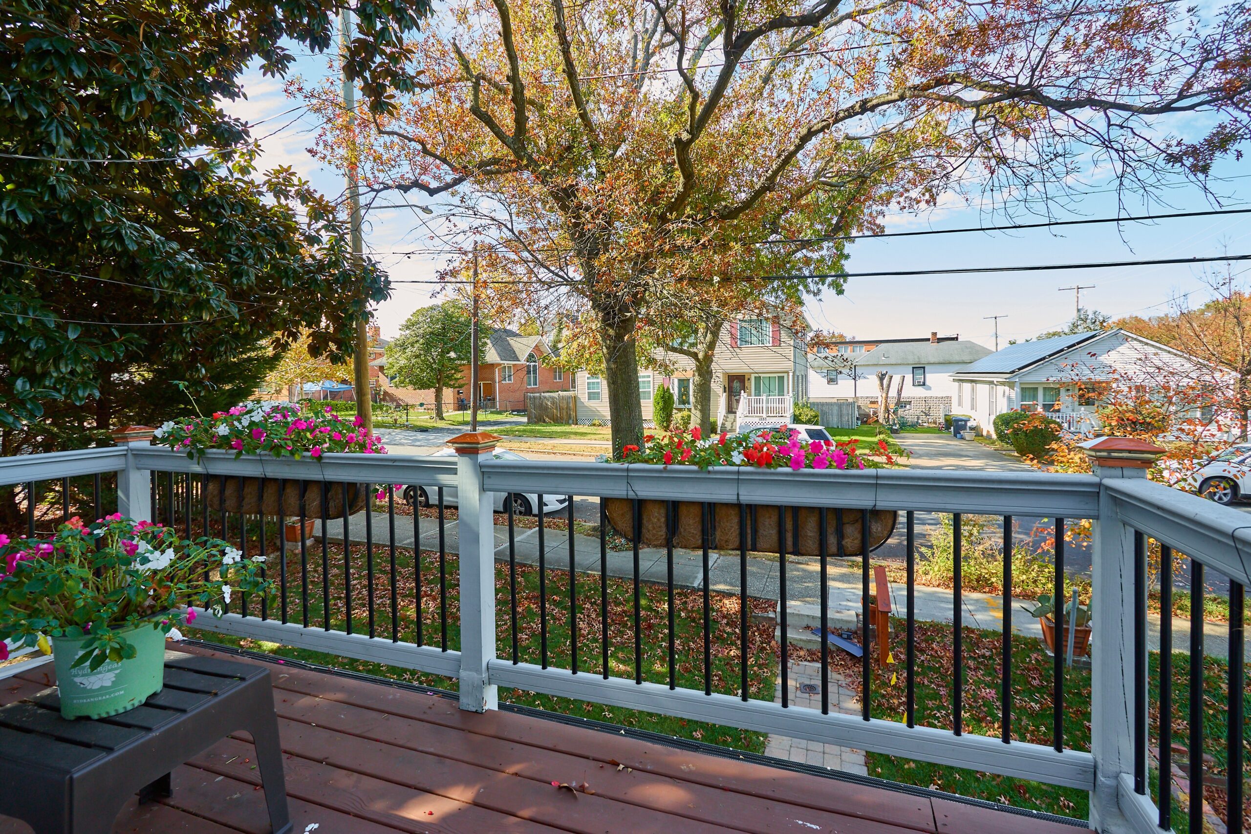 Professional exterior photo of 1219 50th St NE in Washington, DC - showing the view from the 2nd floor balcony looking out the front toward the street on an early fall day