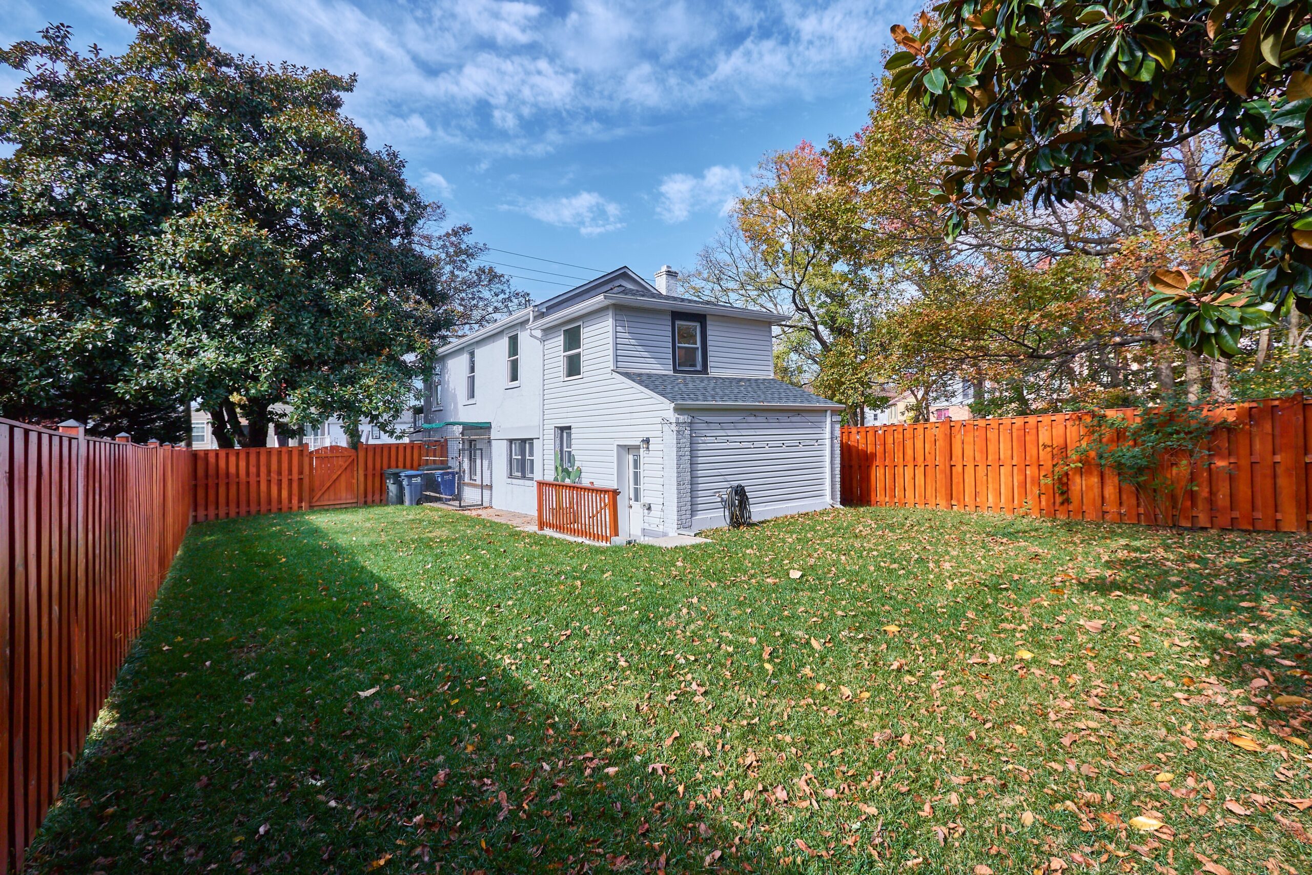 Professional exterior photo of 1219 50th St NE in Washington, DC - showing the rear of the home across a flat backyard that is fully fenced