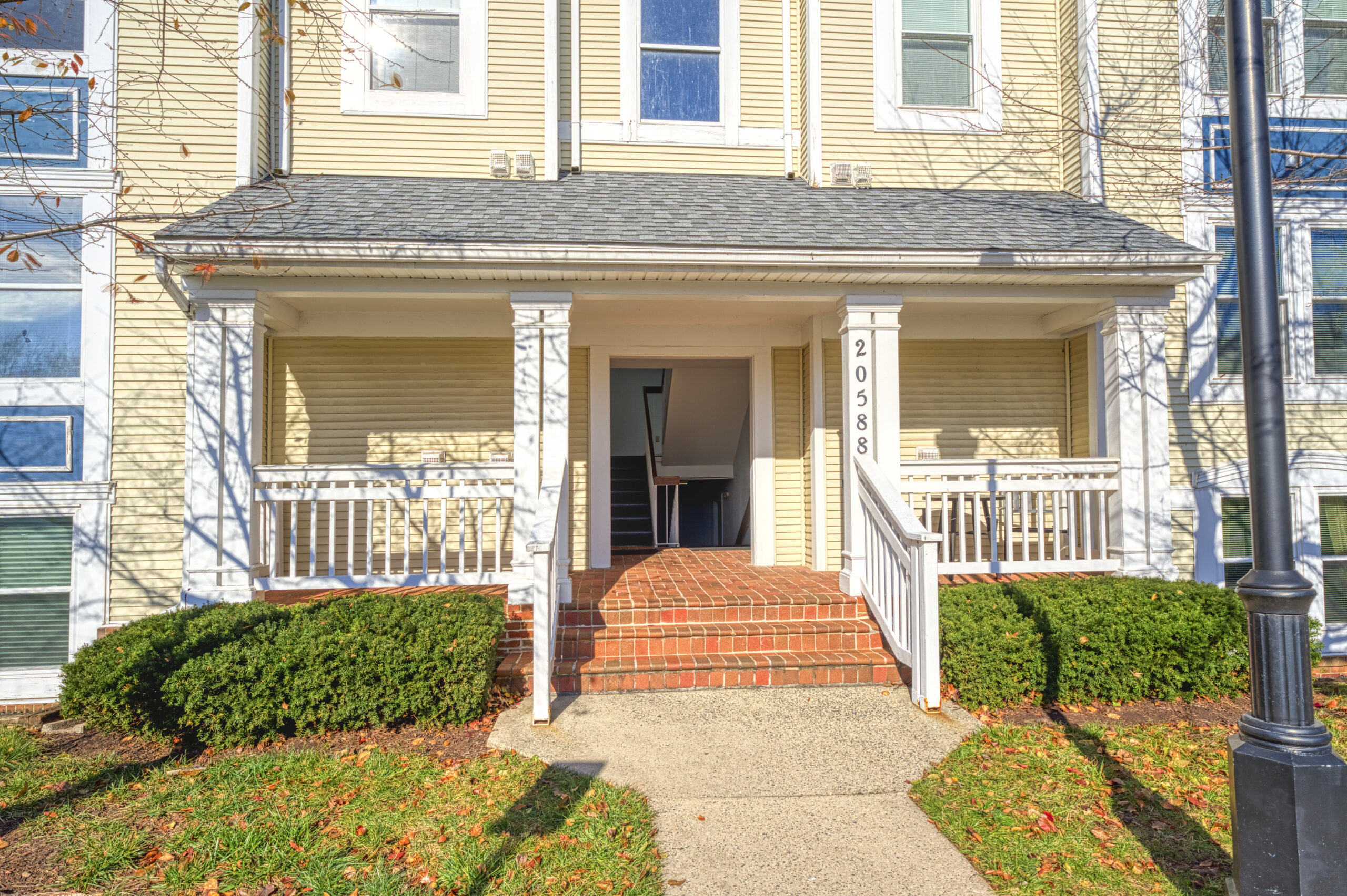 Professional exterior photo of 20588 Cornstalk Ter Unit 101 - Showing the entrance to the condo building with brick front steps and an inviting covered porch.
