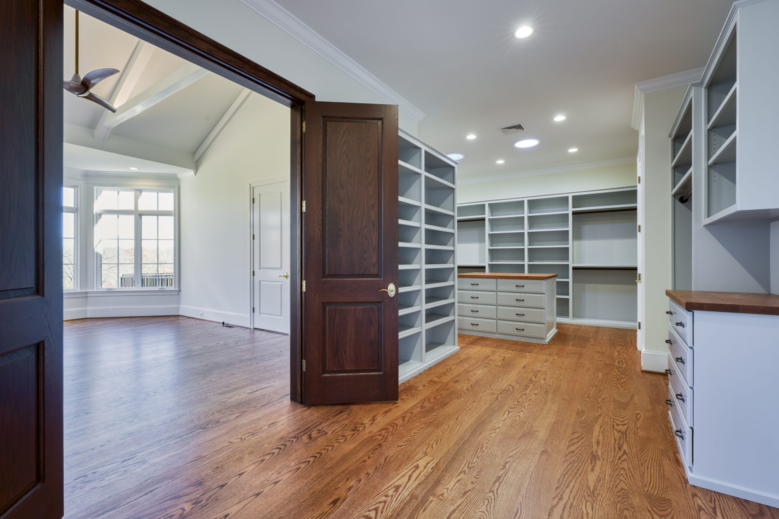 Professional interior photo of custom build new home by Black Oak Construction - showing the primary walk in closet which is fully built out with custom shelves, drawers, and an island with drawers