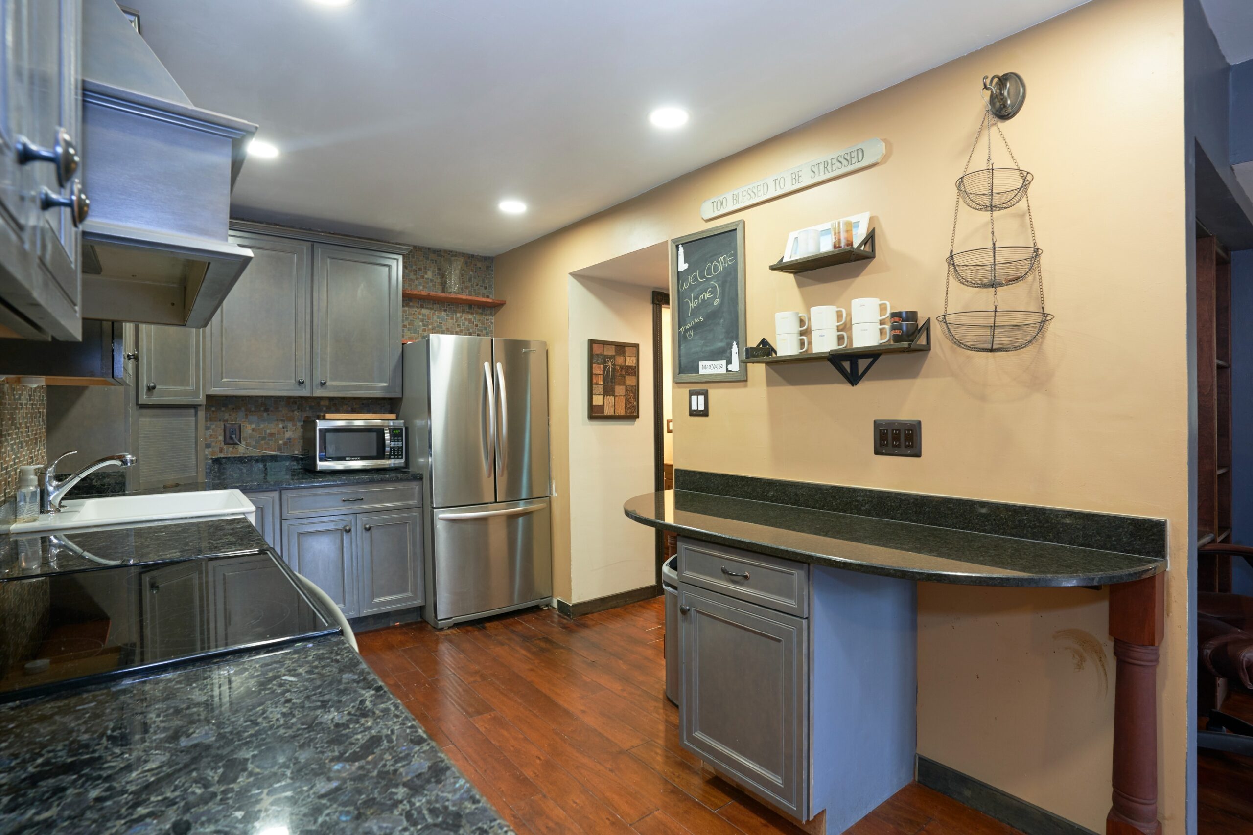 Professional interior photo of 10675 Spring Oak Ct - showing the kitchen with updated grey cabinets, dark granite countertops and non-island build against the wall for additional work and storage space
