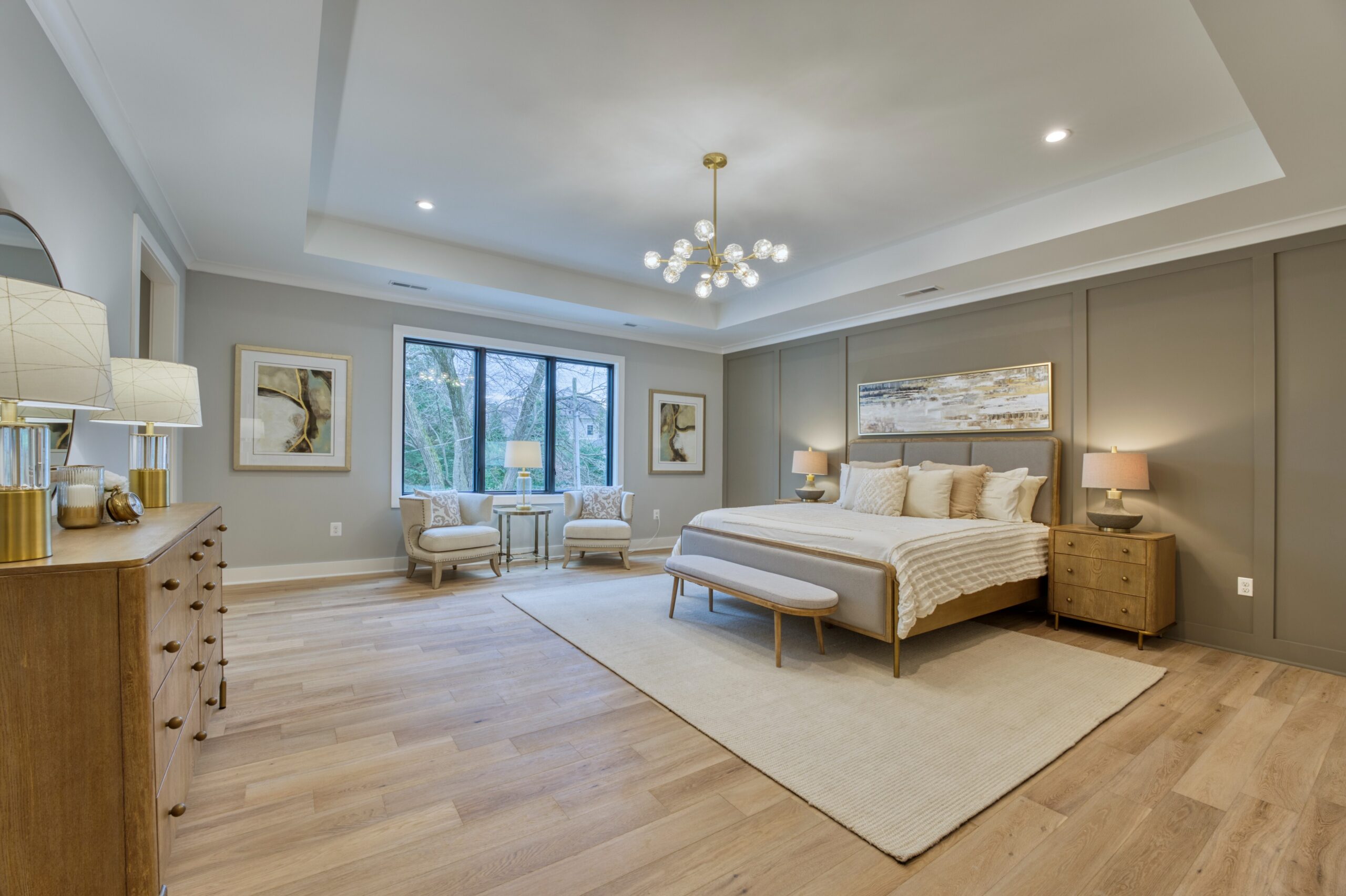 Professional interior photo of new construction home at 3400 N Ohio St - showing the primary bedroom with tray ceiling, grey accent wall, and hardwood floors