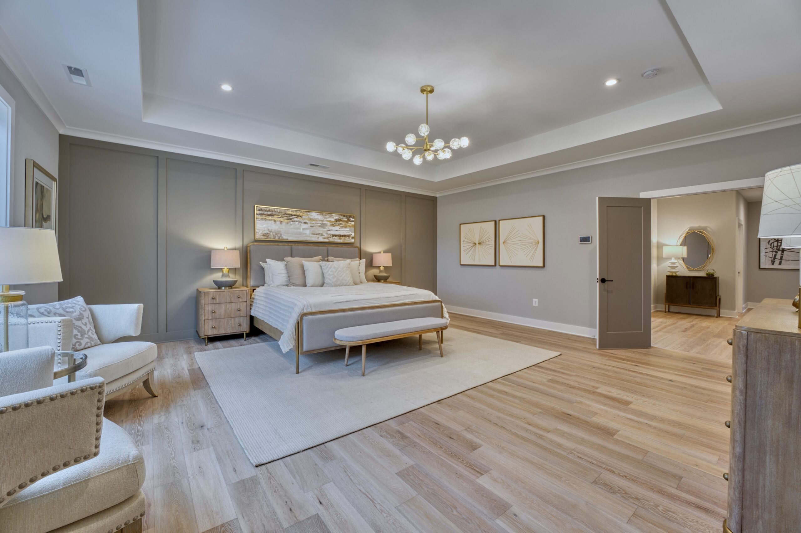 Professional interior photo of new construction home at 3400 N Ohio St - showing the primary bedroom with tray ceiling, grey accent wall, and hardwood floors