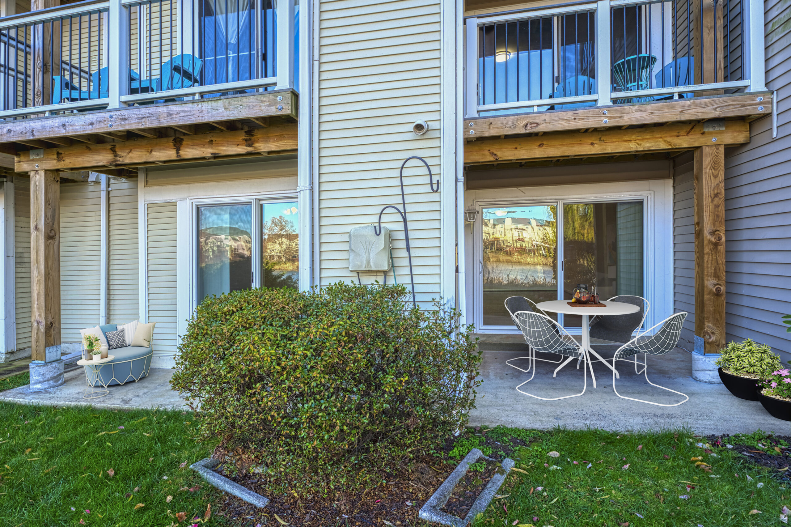 Professional exterior photo of 20588 Cornstalk Ter Unit 101 - Showing the rear patio of the unit on the ground floor which has been virtually staged to show patio furniture