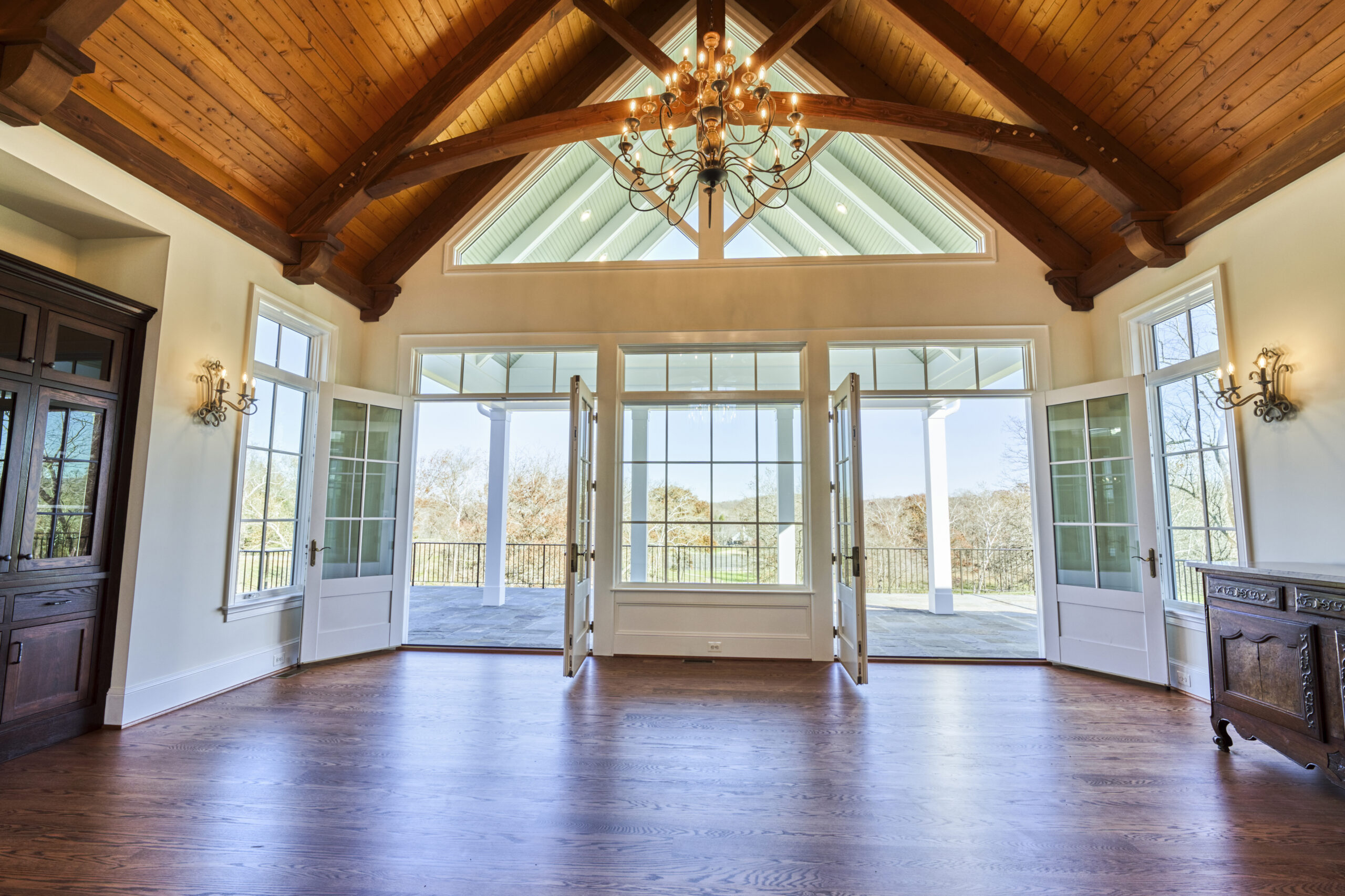 Professional interior photo of custom build new home by Black Oak Construction - showing the great room with hardwood floors, vaulted wooden ceiling with wooden trusses, 2 sets of double doors leading out to the rear covered patio