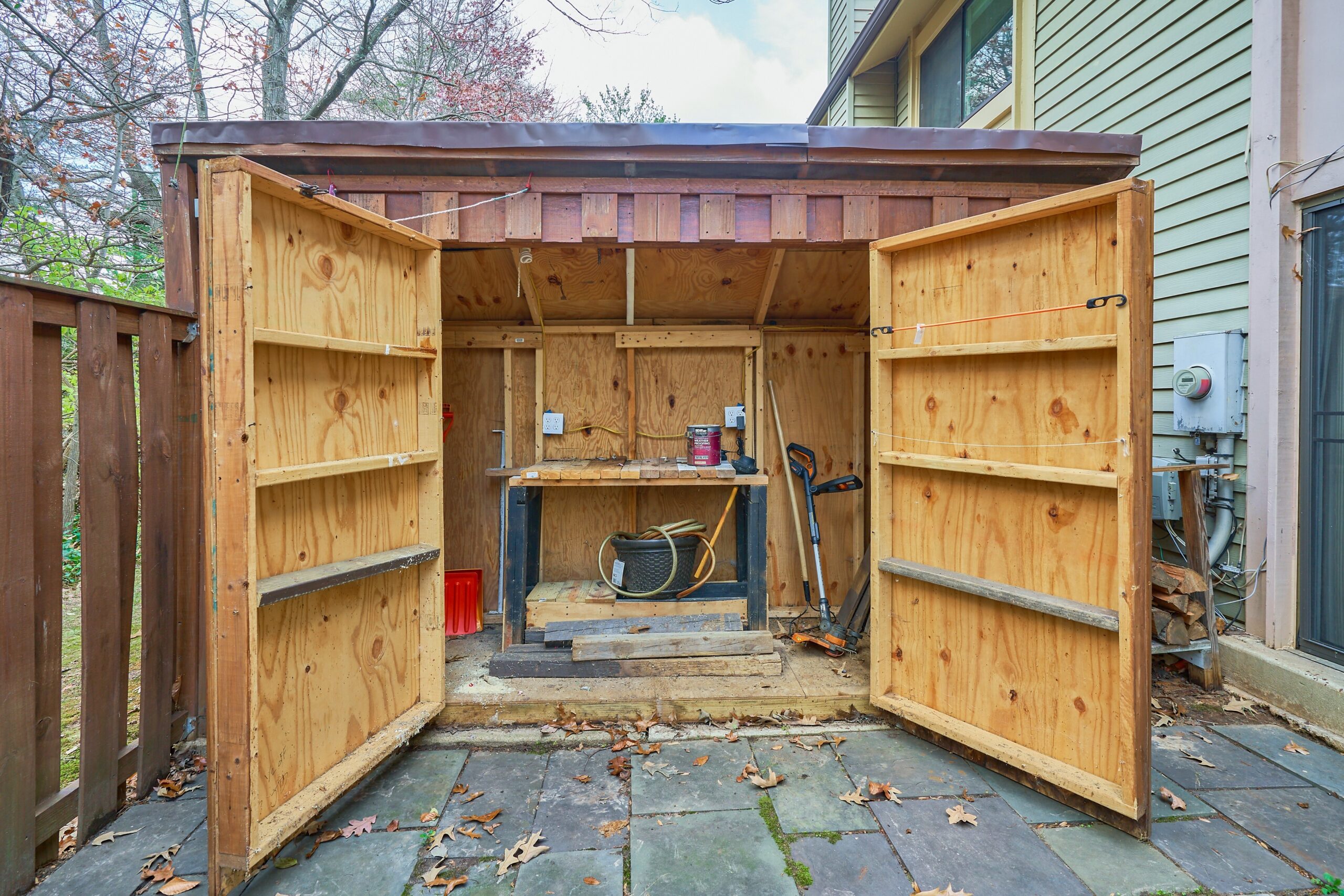 Professional exterior photo of 10675 Spring Oak Ct - showing the backyard work shed opened up to reveal the work table and storage area for tools and equipment on a stone patio