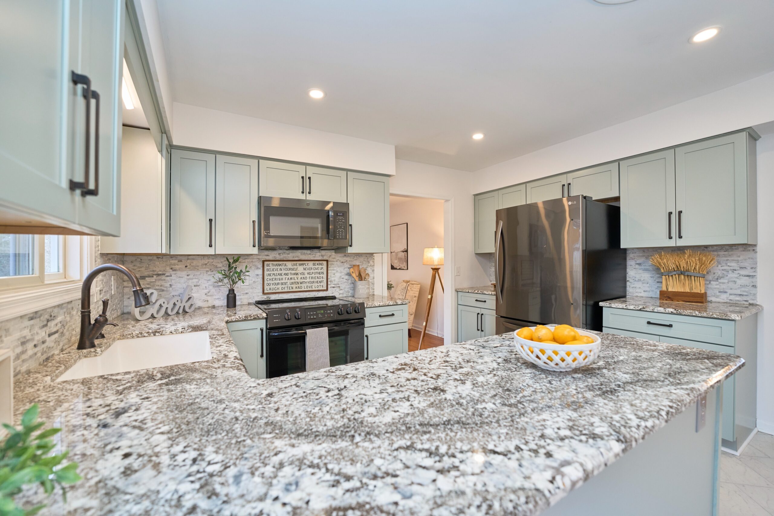 Professional interior photo of 3103 Indian Run Rd - showing the kitchen with unique granite countertops wrapping around, newer grey cabinets with updated hardware, and stainless and black appliances