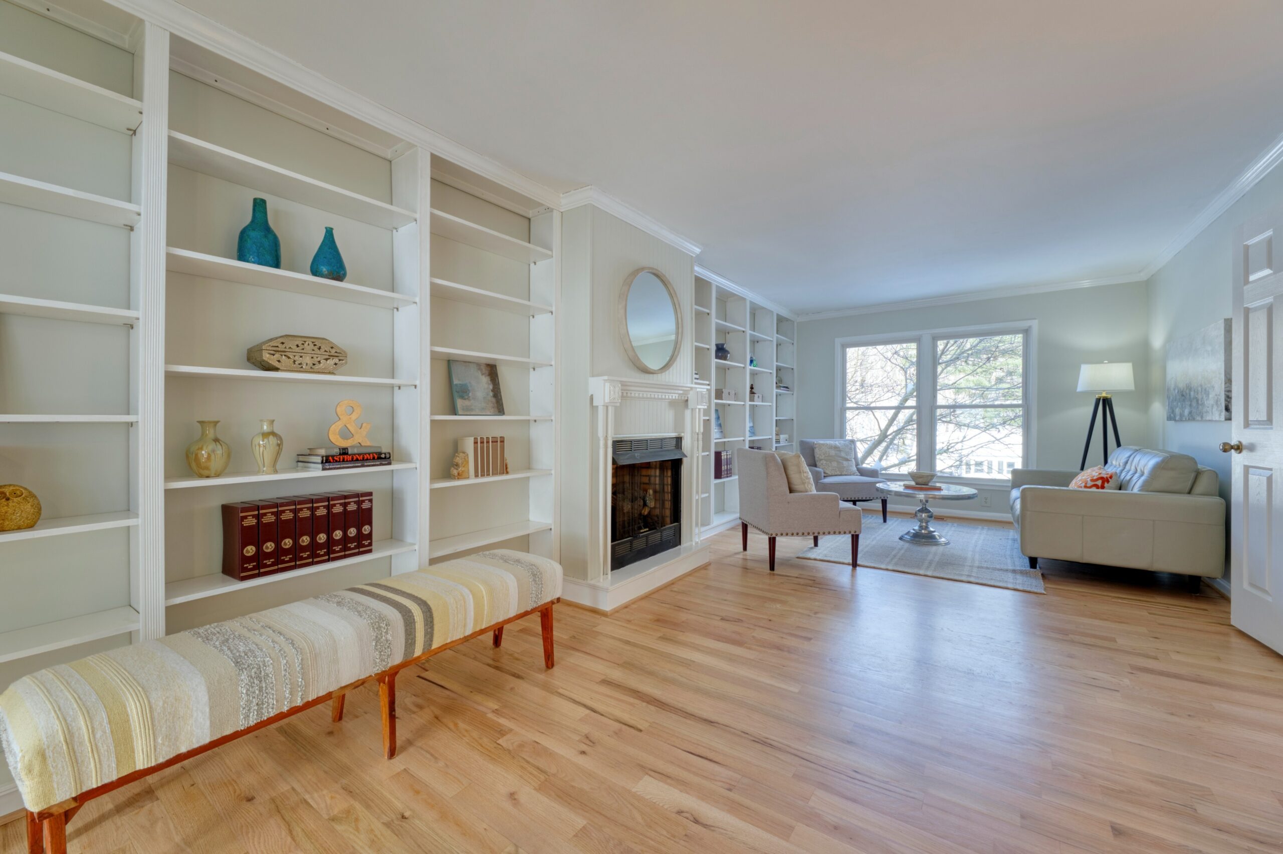 Professional interior photo of 9515 Center St in Vienna, Virginia - showing the living room area with hardwood floors, wall to wall build in shelves on either side of a fireplace