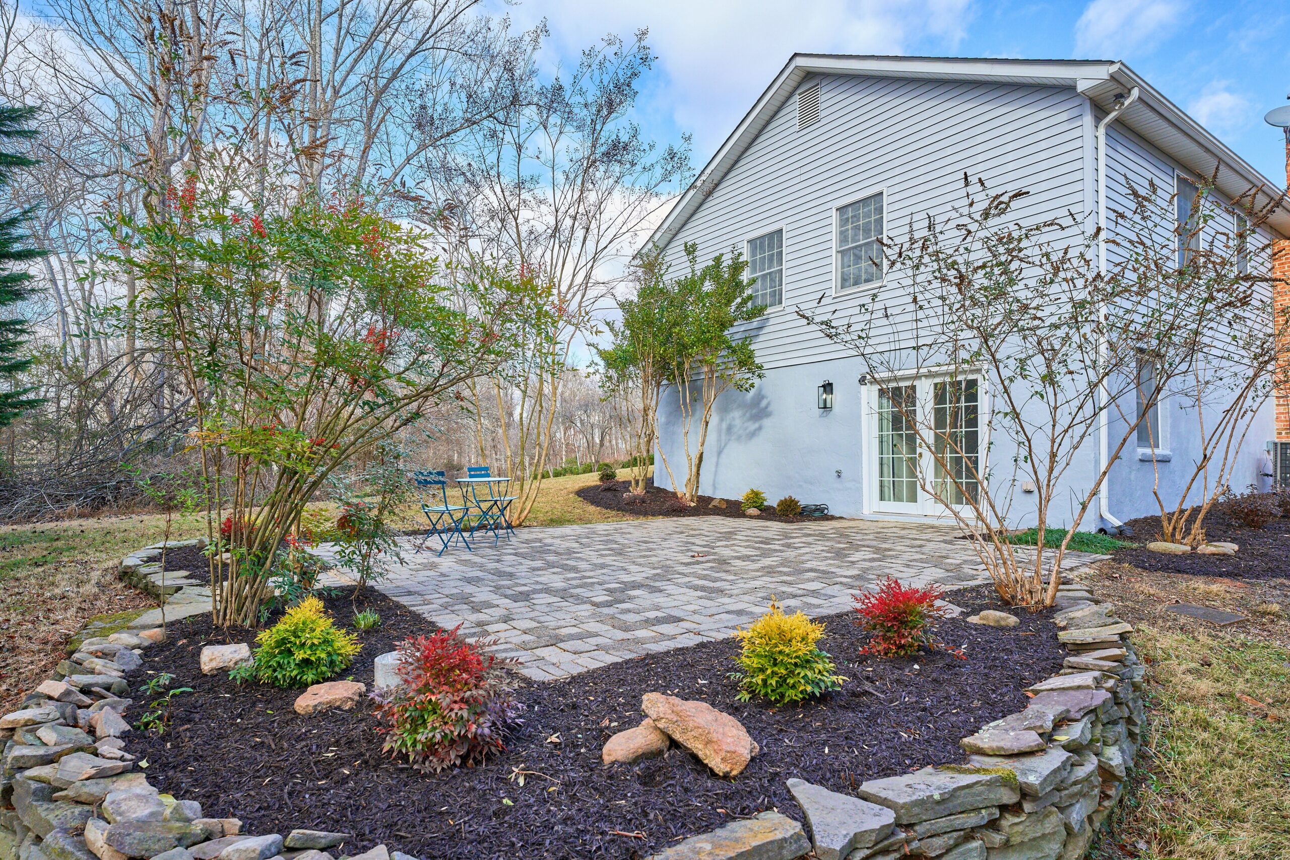 Professional exterior photo of 3103 Indian Run Rd - showing the stone patio and landscaping just off the lower level of the grey rambler