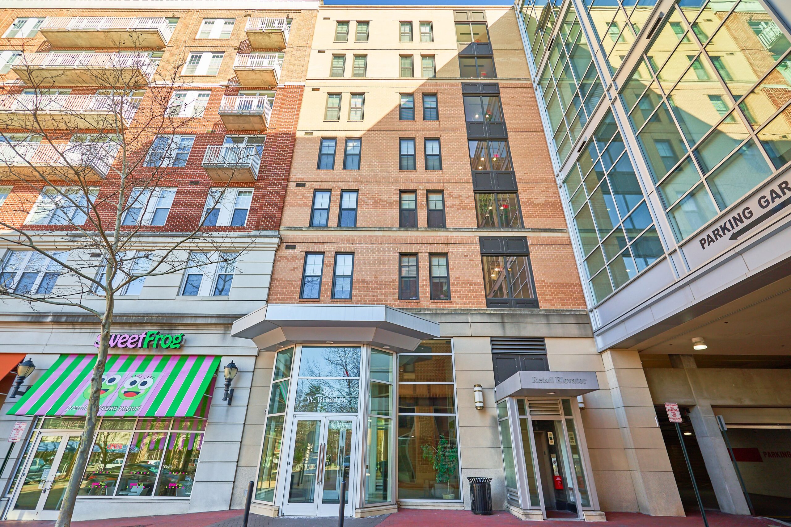Professional exterior photo of 444 W Broad St Unit 631 - showing the full front facade of The Spectrum apartments between a Sweet Frog and a parking garage.