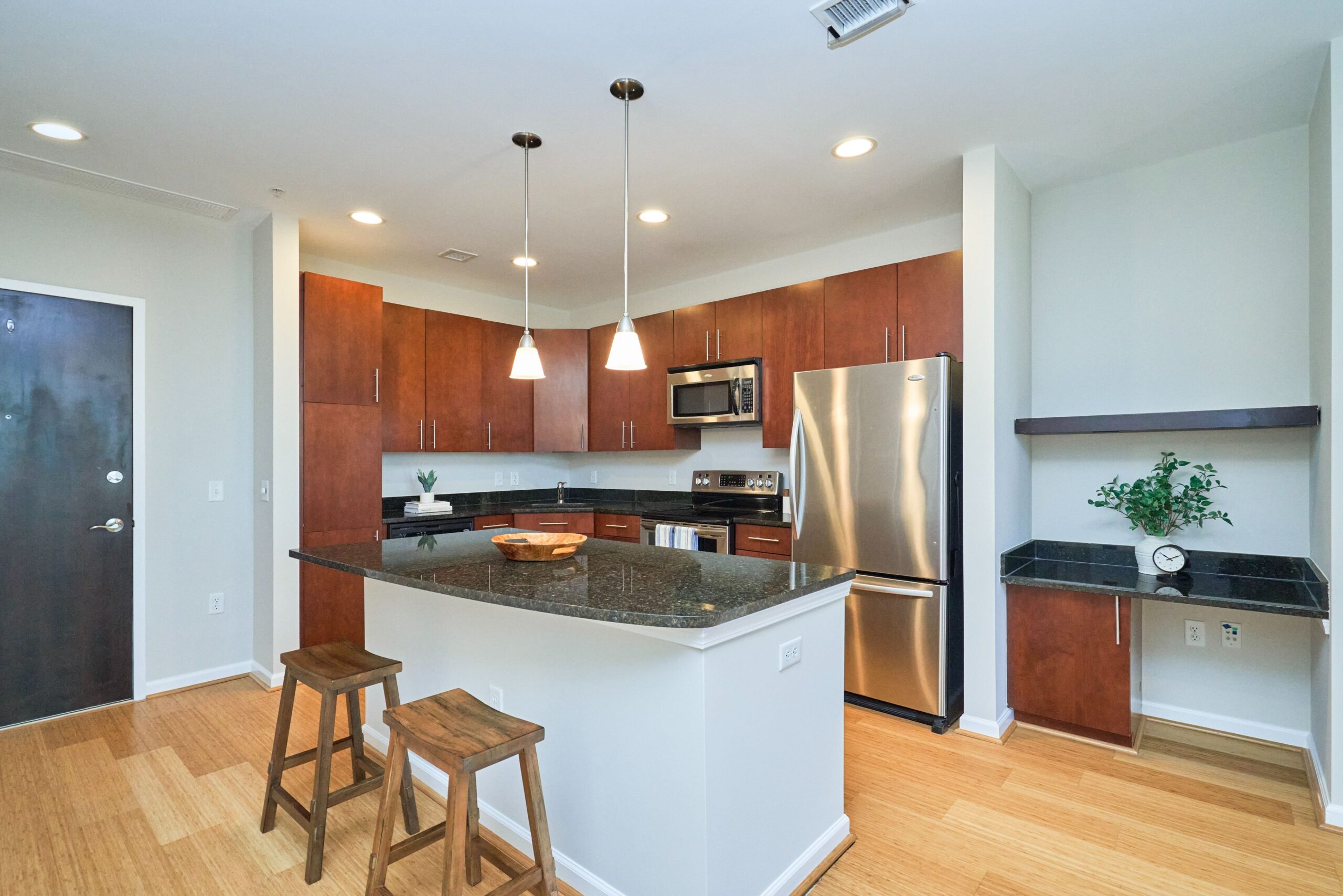 Professional interior photo of 444 W Broad St Unit 631 - showing the open kitchen with granite island next to a desk area with a shelf and under cabinet