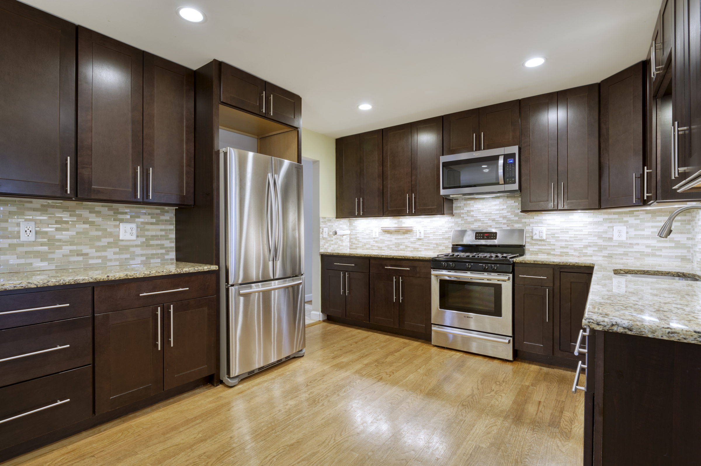 Professional interior photo of 2624 Depaul Dr in Vienna, VA - showing the remodeled kitchen with dark cabinets, stainless pulls, stainless appliances, gas range, and granite counters 