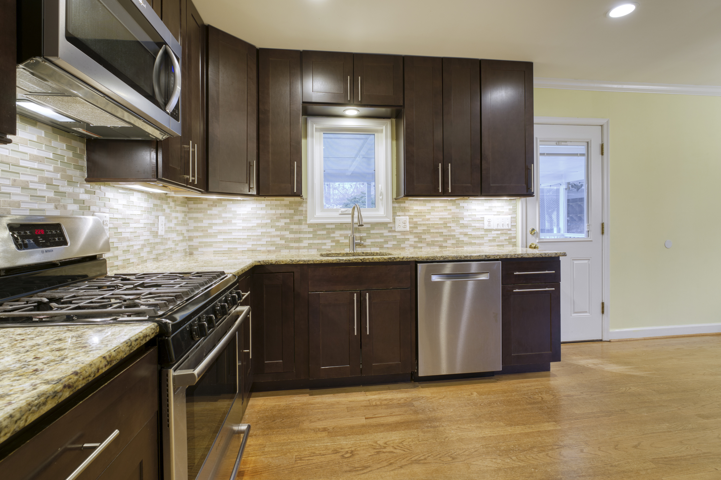 Professional interior photo of 2624 Depaul Dr in Vienna, VA - showing the remodeled kitchen with dark cabinets, stainless pulls, stainless appliances, gas range, and granite counters 